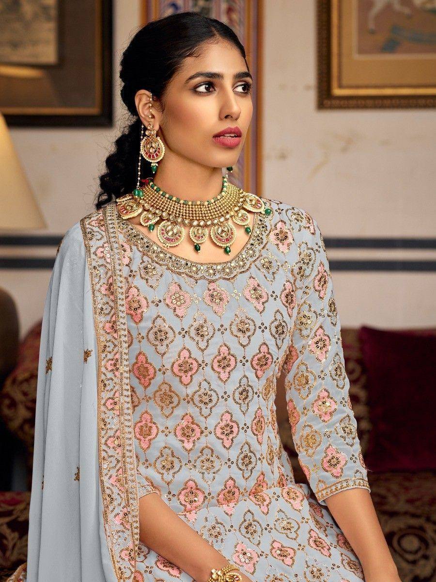 Light blue embroidered salwar kameez with pink gold motifs, paired with traditional jewelry