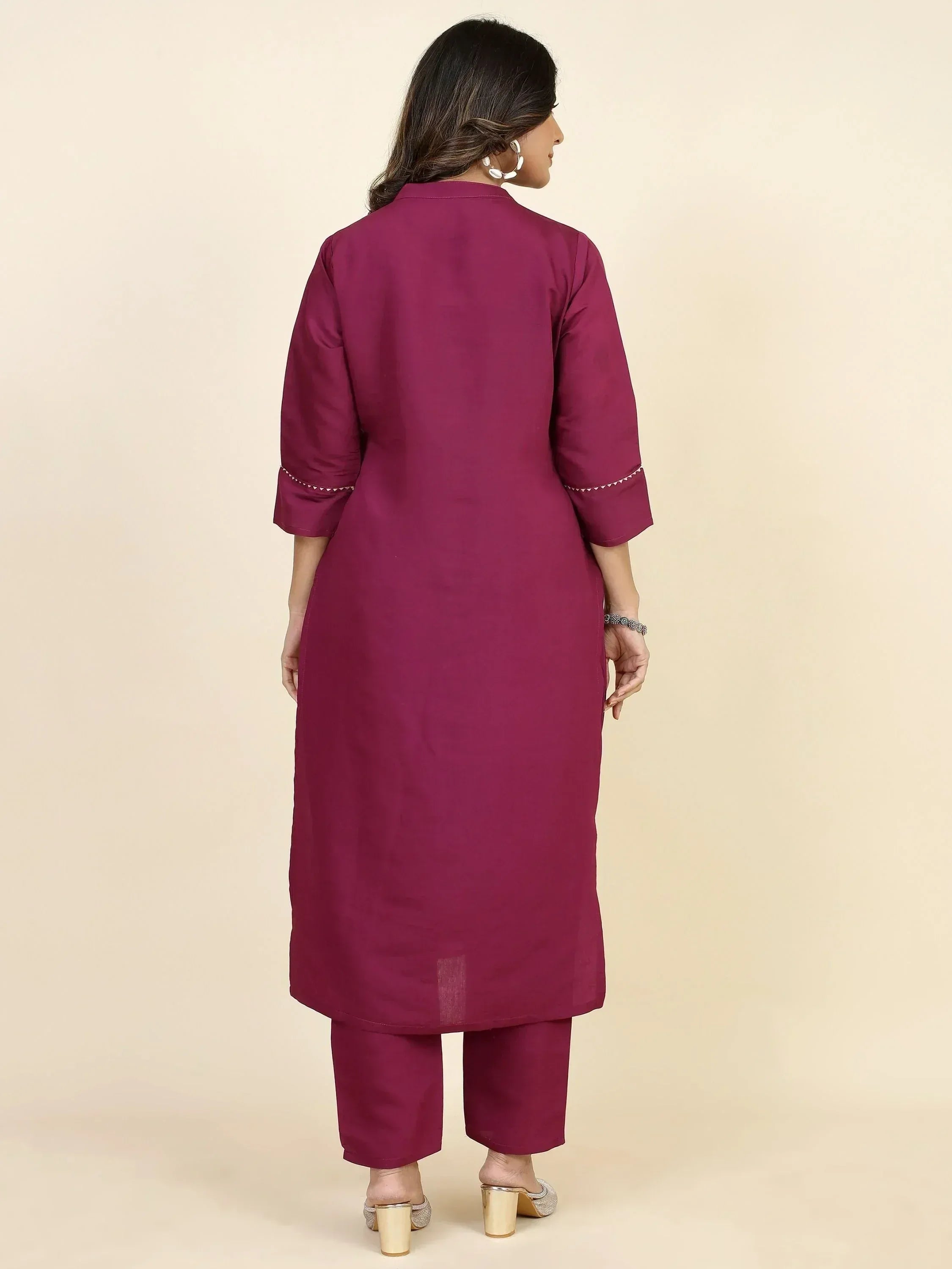 Back view of woman in maroon ethnic kurta with embroidered cuffs, matching pants, and heels