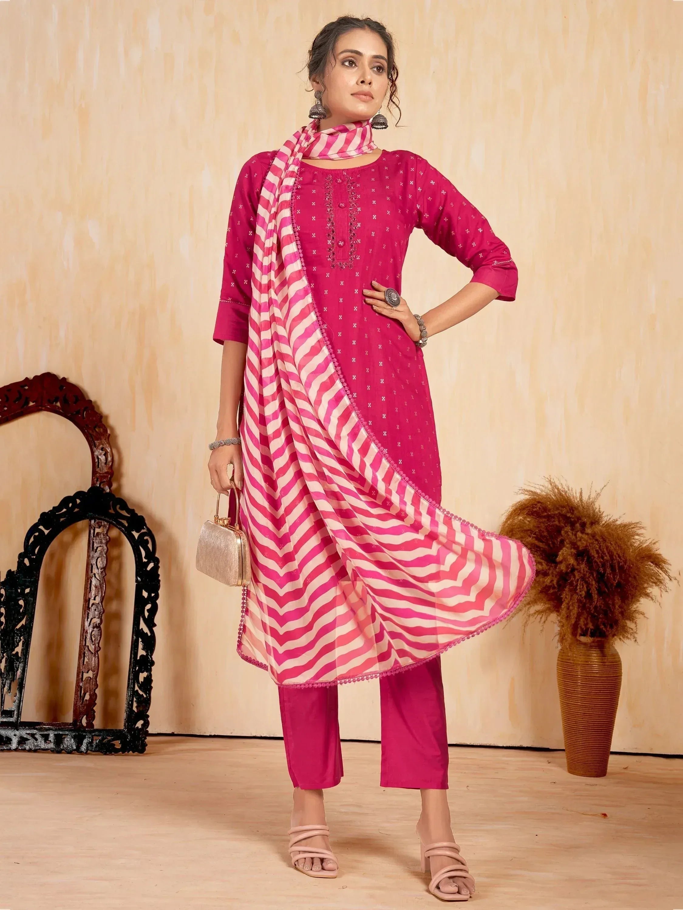 Woman in magenta ethnic kurta set with striped dupatta and straight pants, standing indoors