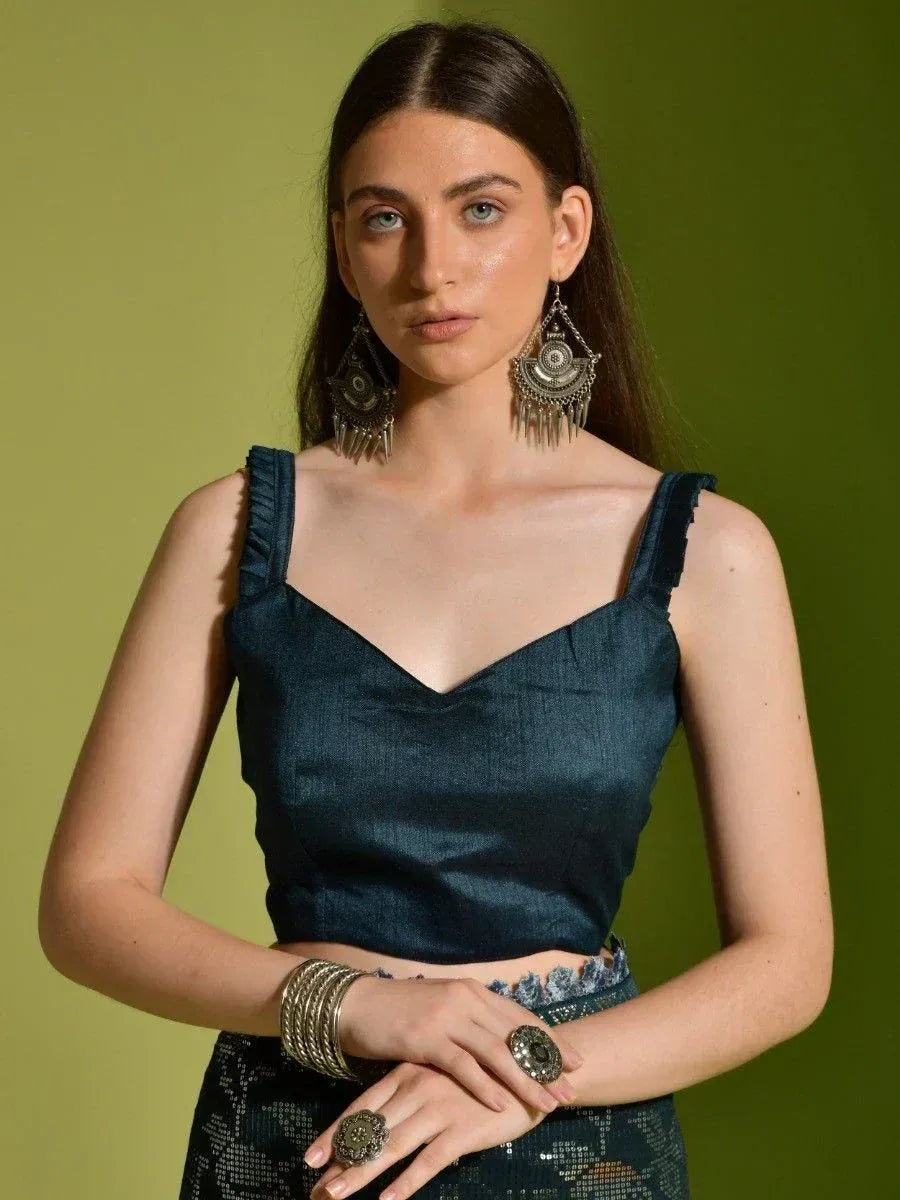 Woman in dark blue ethnic crop top with ruffled straps, paired with embellished skirt and tribal jewelry
