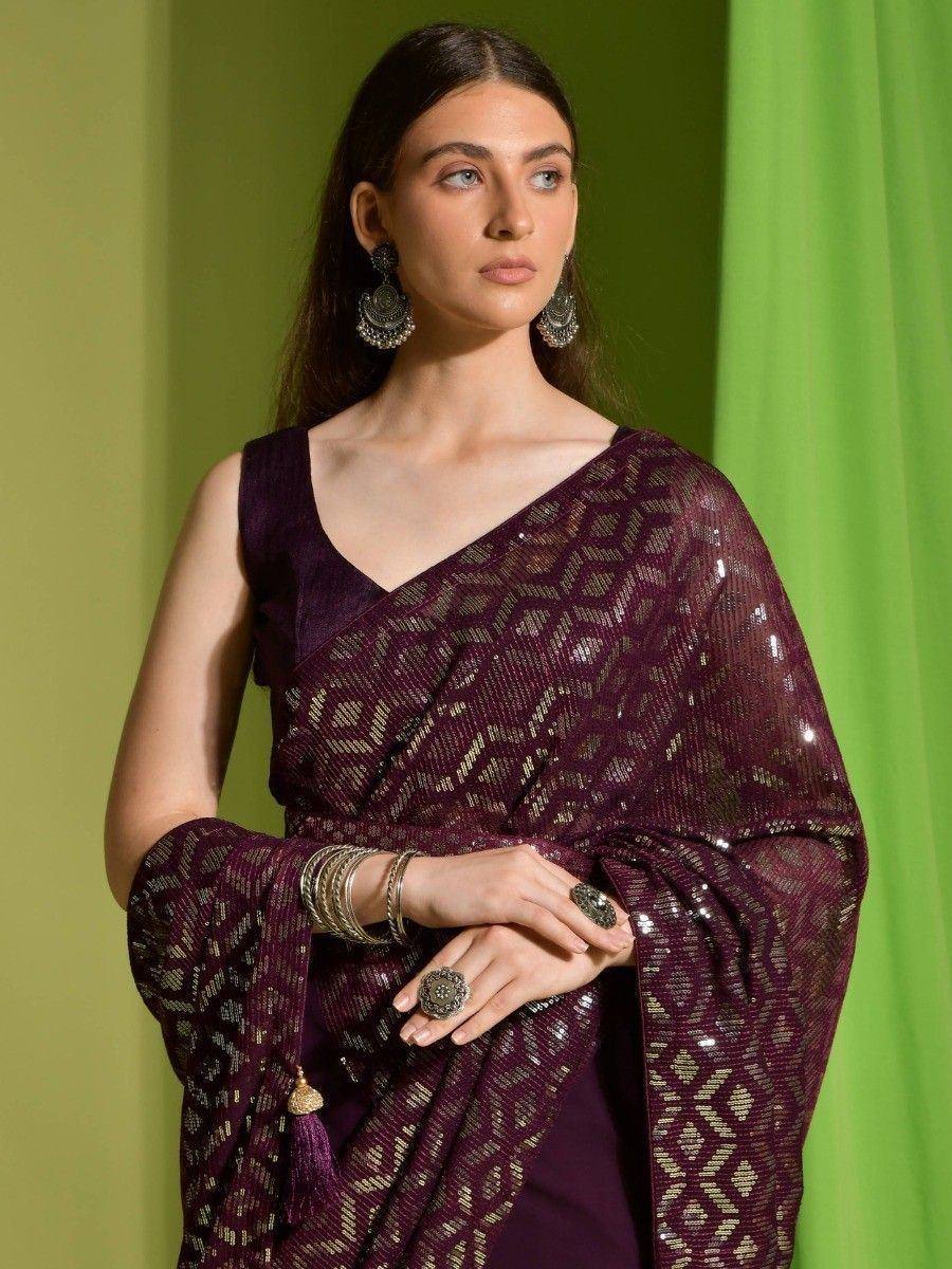 Elegant maroon ethnic saree with gold geometric patterns and sequin detailing, paired with statement jewelry.