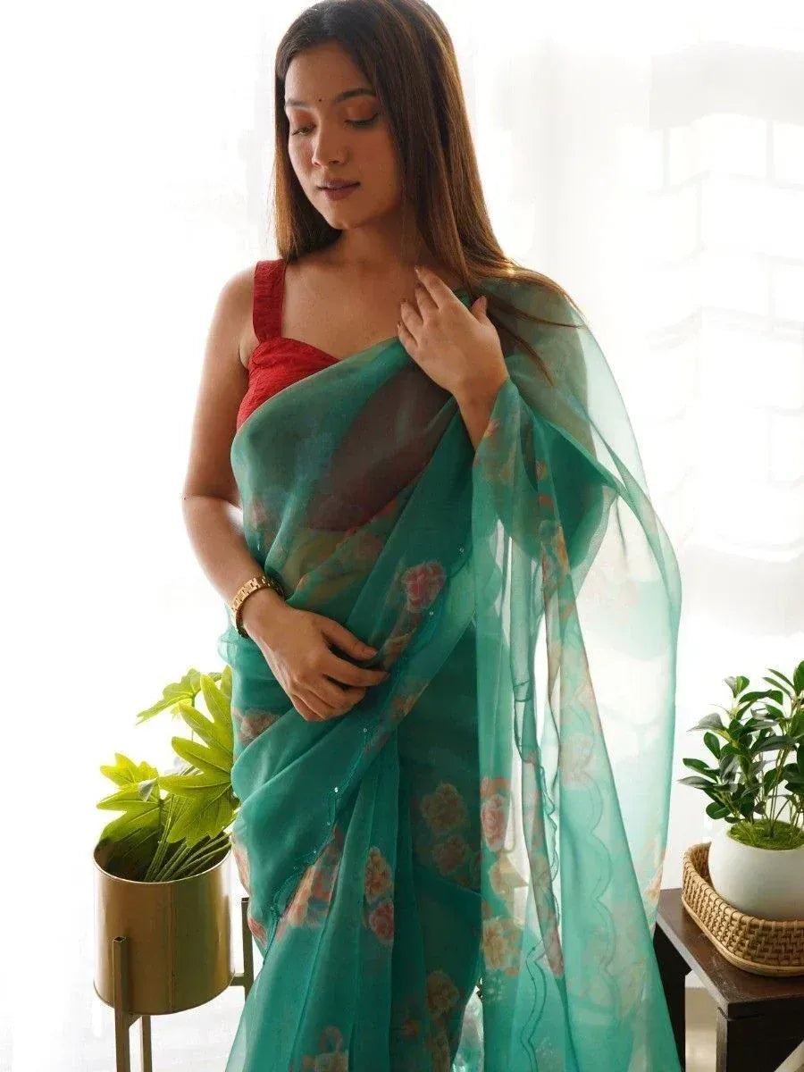 Woman in teal floral saree with red blouse, elegant ethnic wear for festive occasions