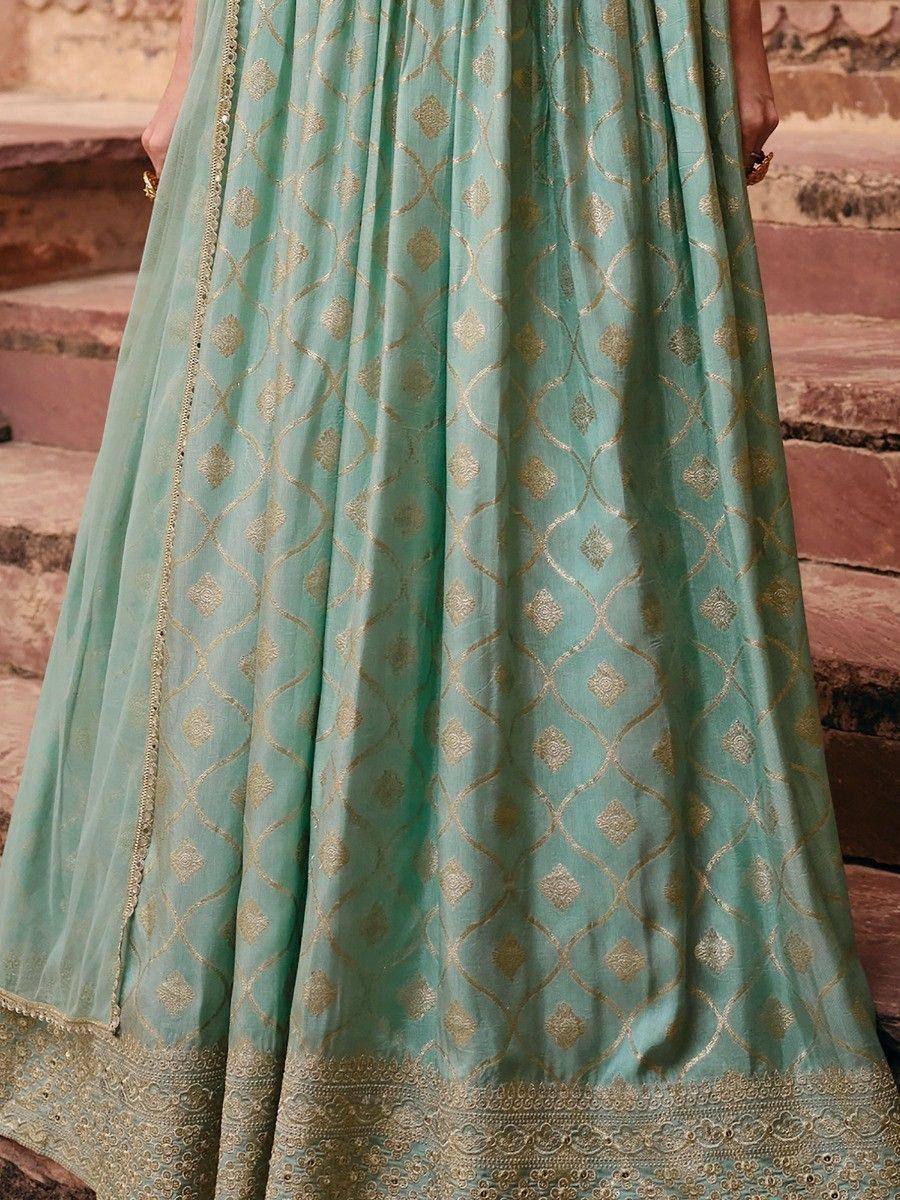 Mint green ethnic gown with gold geometric print and embroidered hem, perfect for Indian occasions