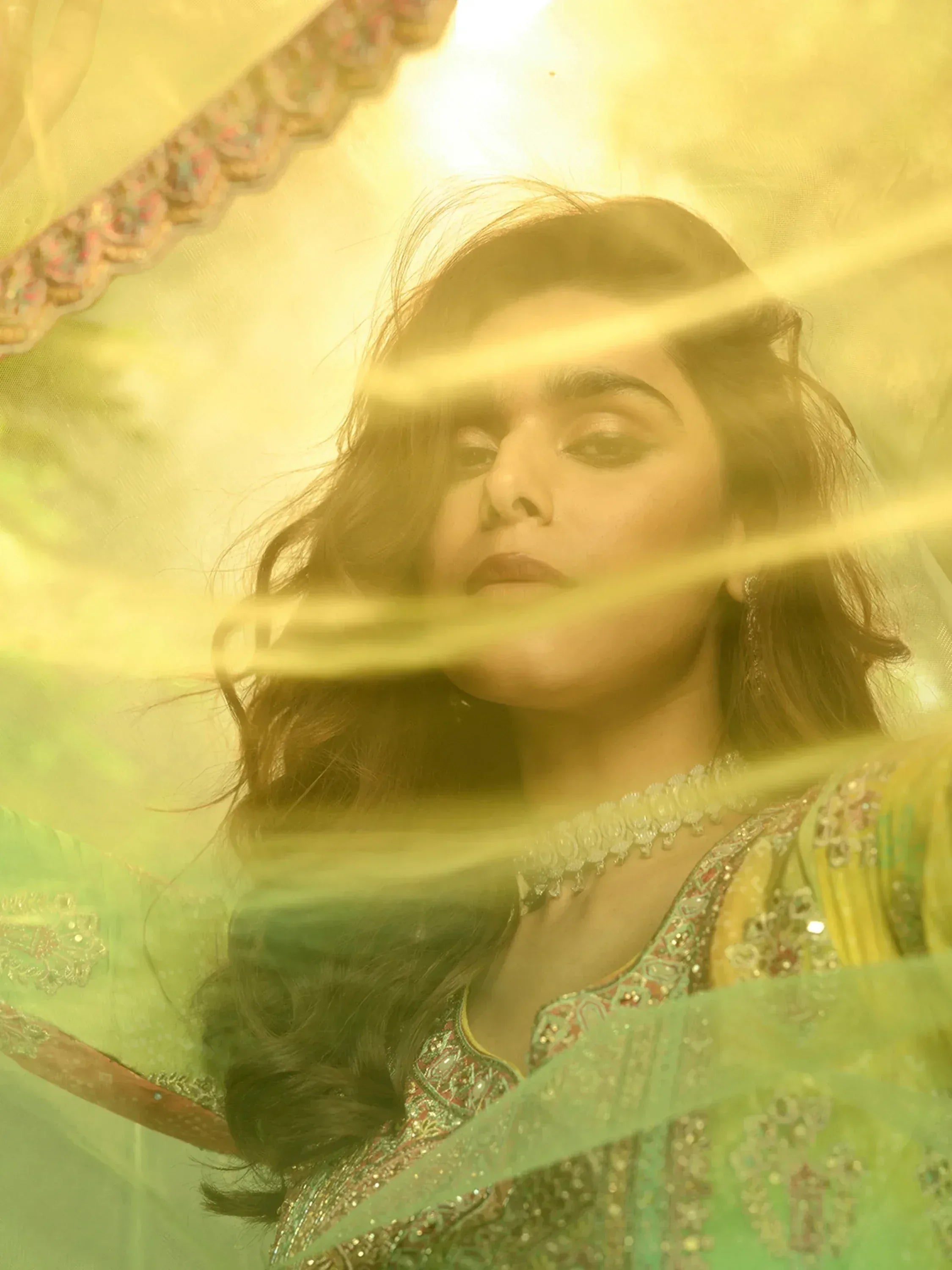 Woman in elegant green and gold embroidered ethnic wear with sheer dupatta, perfect for Indian festive occasions.