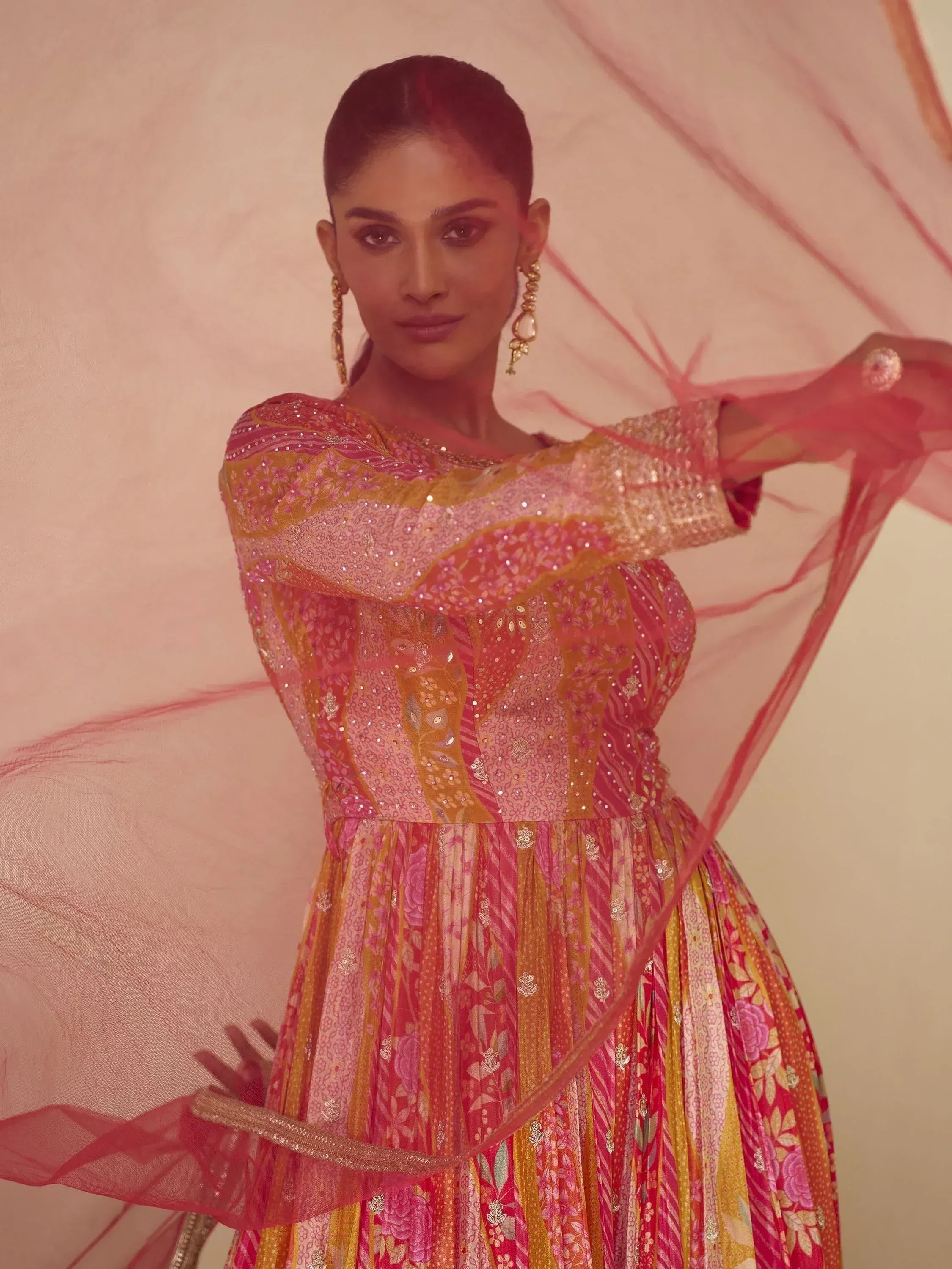 Woman in vibrant pink and gold embroidered ethnic gown with sheer dupatta, perfect for Indian weddings and festivals