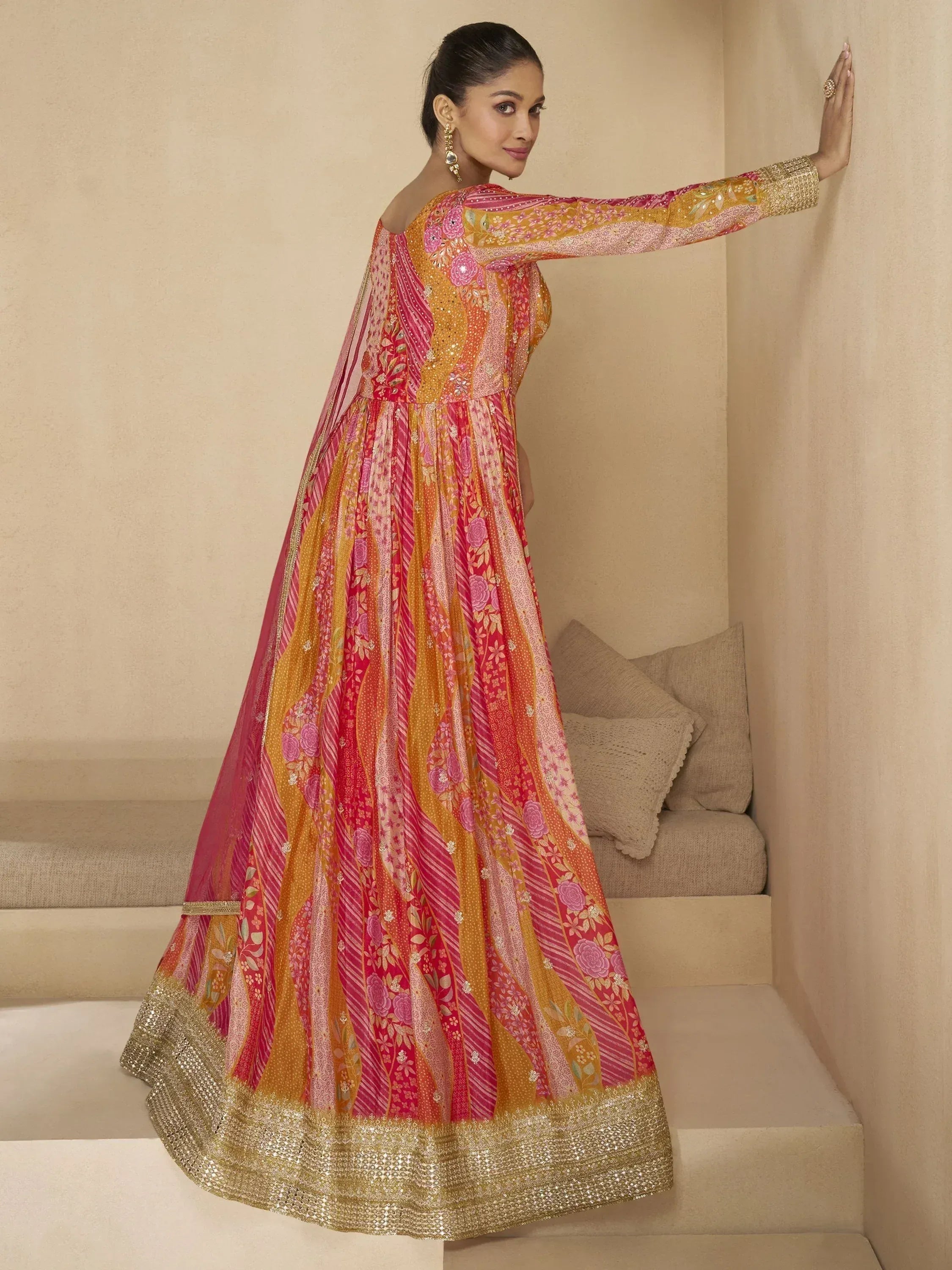 Woman in vibrant pink and gold floral anarkali gown with sequin border, ideal for Indian ethnic occasions