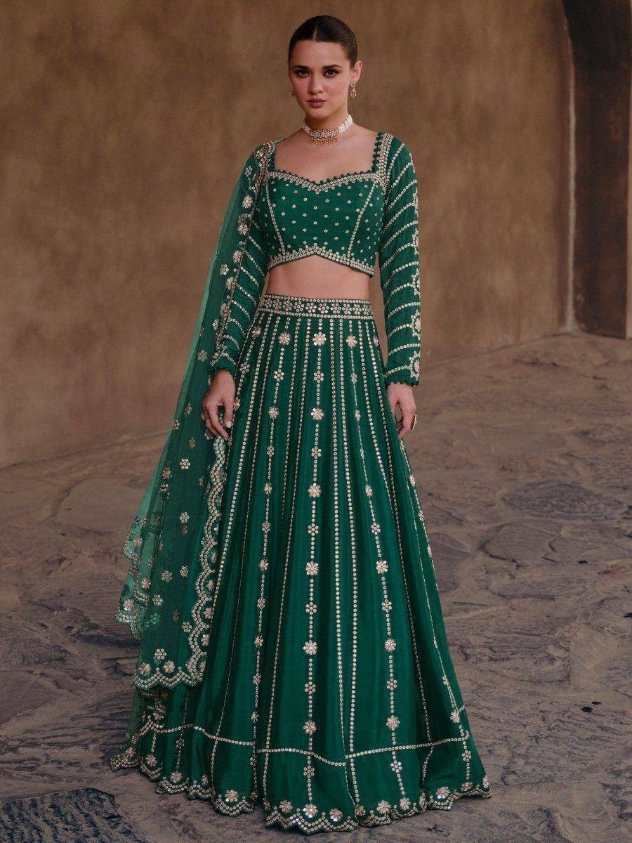 Emerald green designer lehenga choli with intricate gold embroidery and sheer dupatta, perfect for weddings.