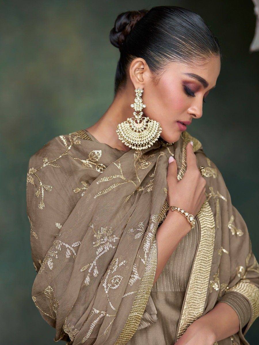 Elegant Indian ethnic saree with gold embroidery, paired with statement jhumka earrings and traditional jewelry.