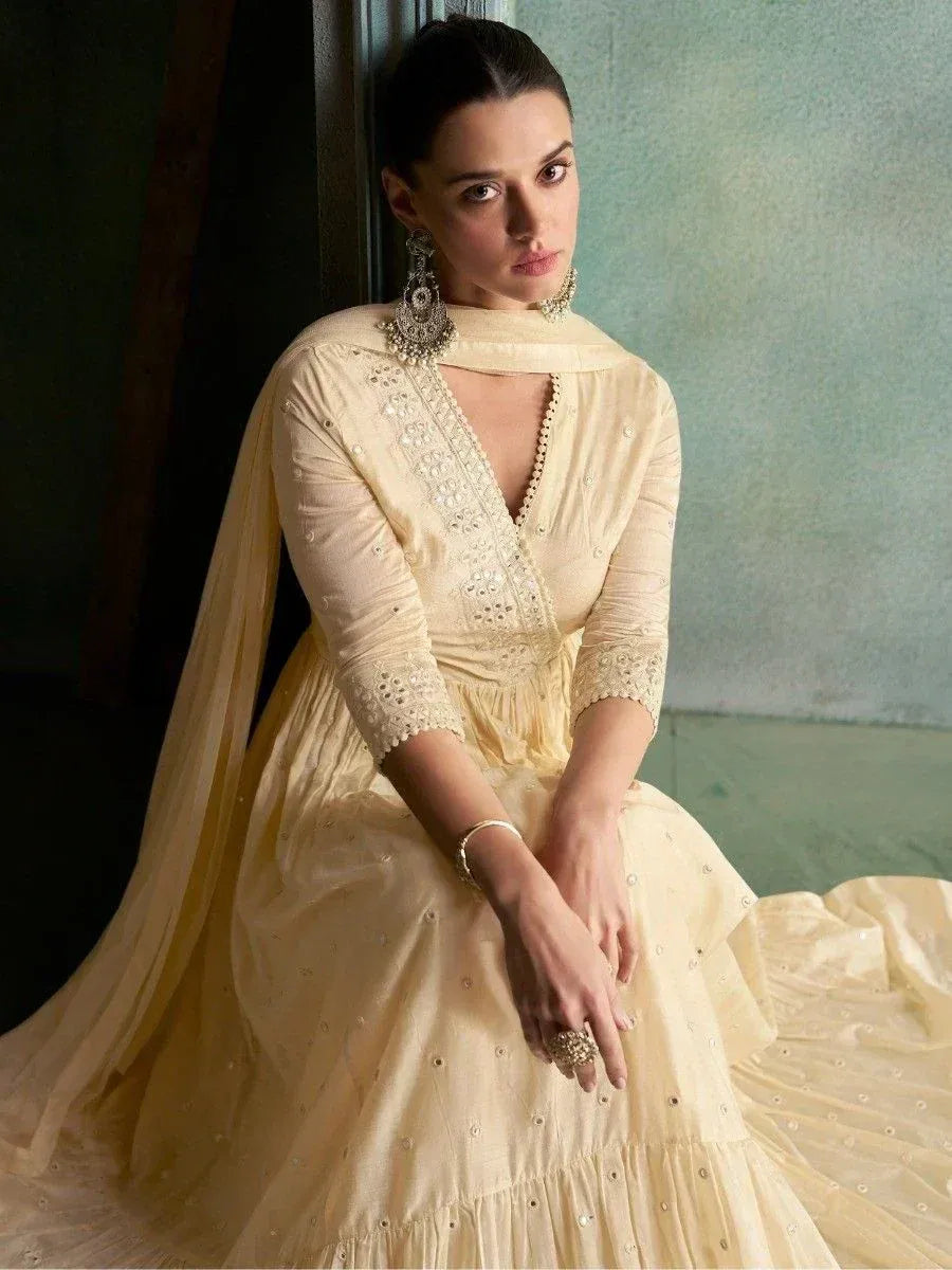 Elegant cream ethnic gown with intricate embroidery and sheer dupatta, perfect for Indian weddings and festive occasions.