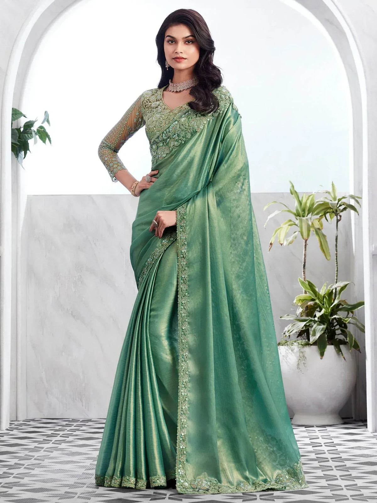 Elegant green designer saree with intricate embroidery and sheer sleeves, perfect for Indian ethnic occasions.