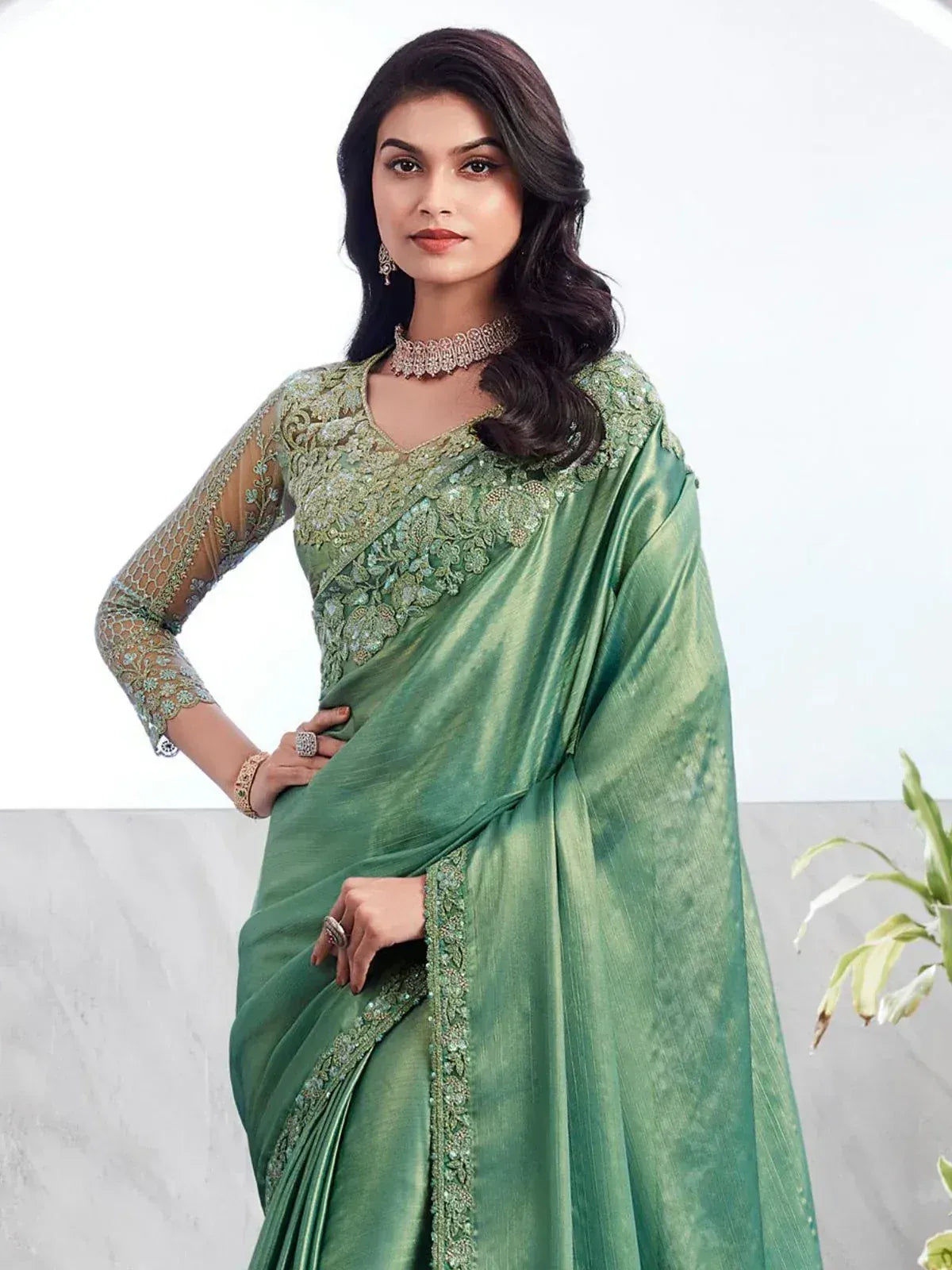 Elegant green designer saree with intricate embroidery and sheer sleeves, perfect for Indian ethnic occasions.