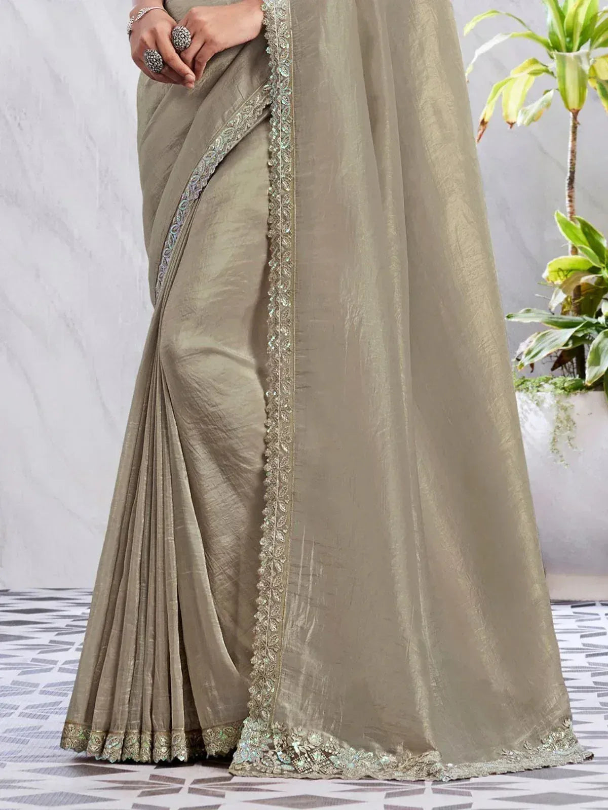 Elegant olive green saree with intricate silver embroidery and sequin border, perfect for Indian ethnic occasions.