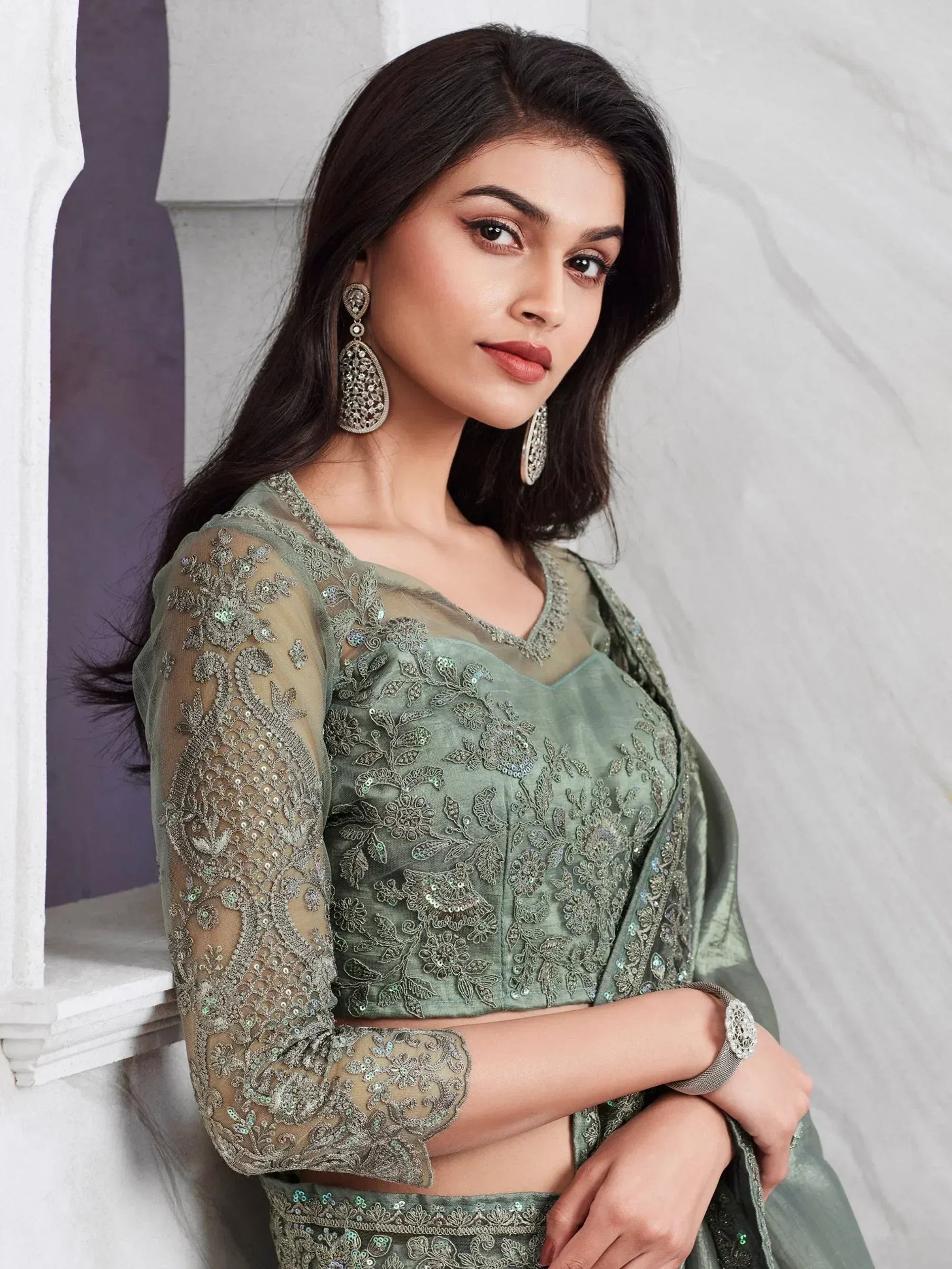 Elegant sage green embroidered lehenga choli with sheer sleeves and floral detailing, perfect for Indian ethnic occasions.