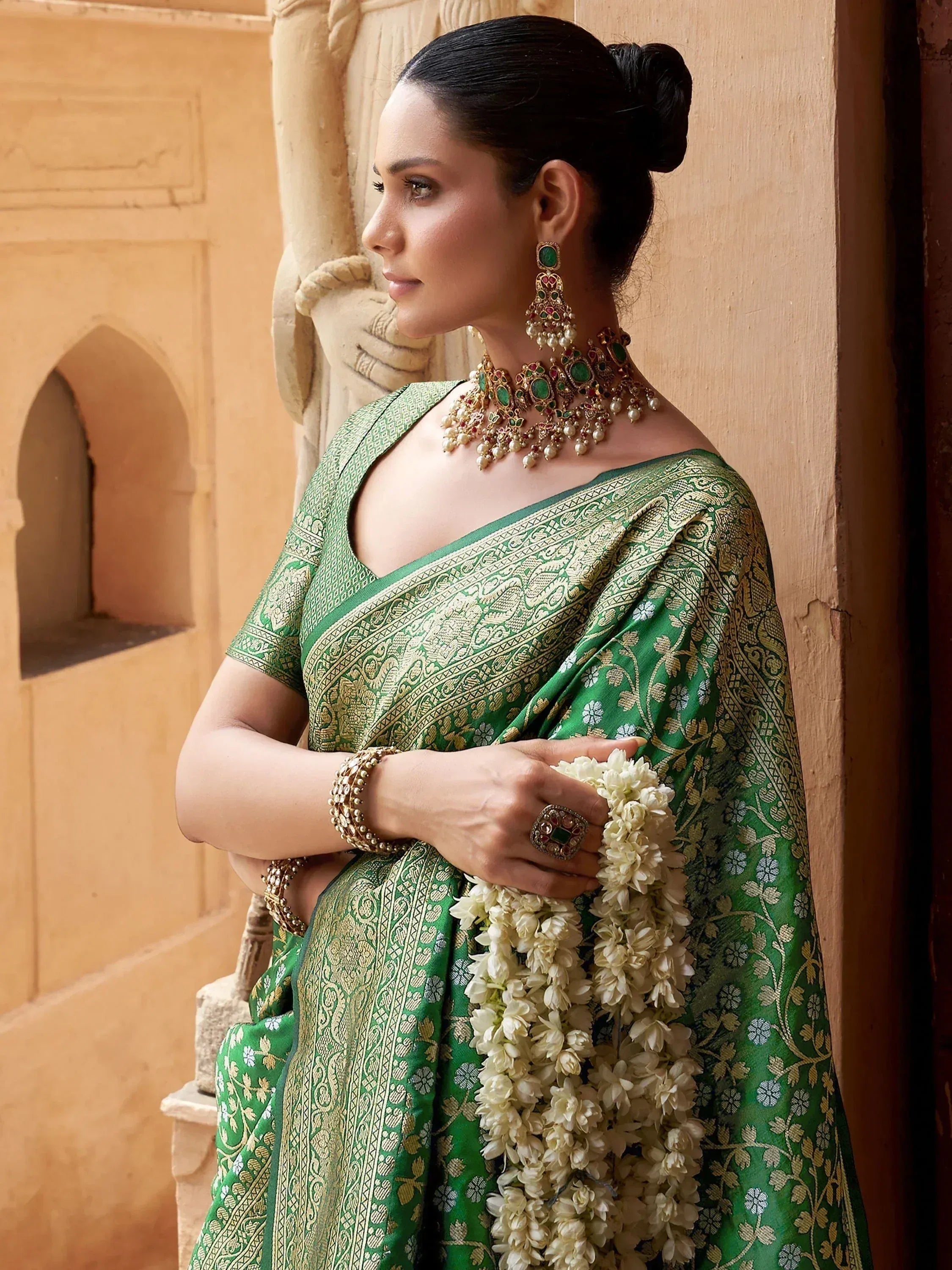 Elegant woman in green and gold designer saree with traditional jewelry and jasmine garland, Indian ethnic wear