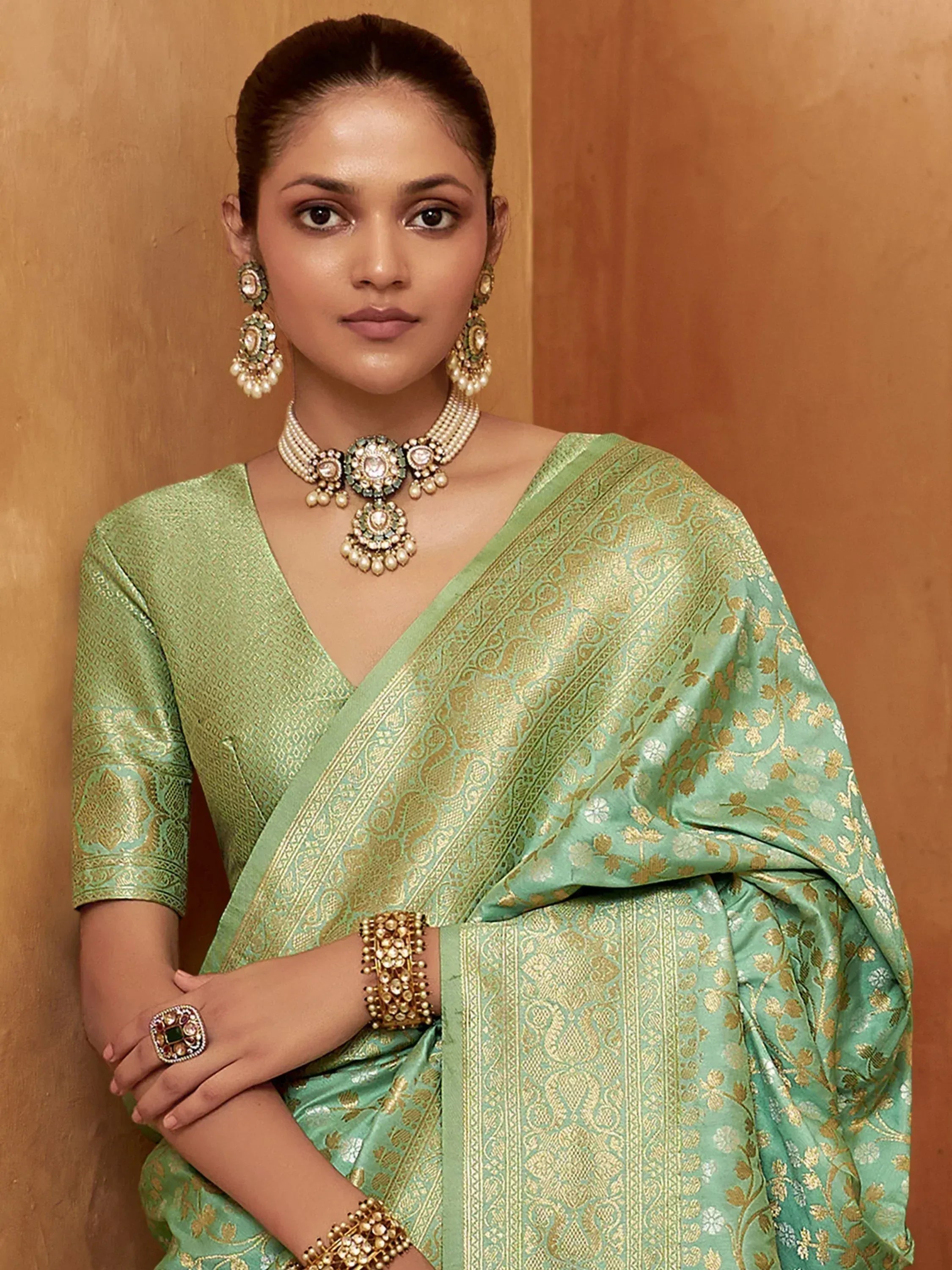 Woman in elegant green and gold embroidered saree with traditional Indian jewelry