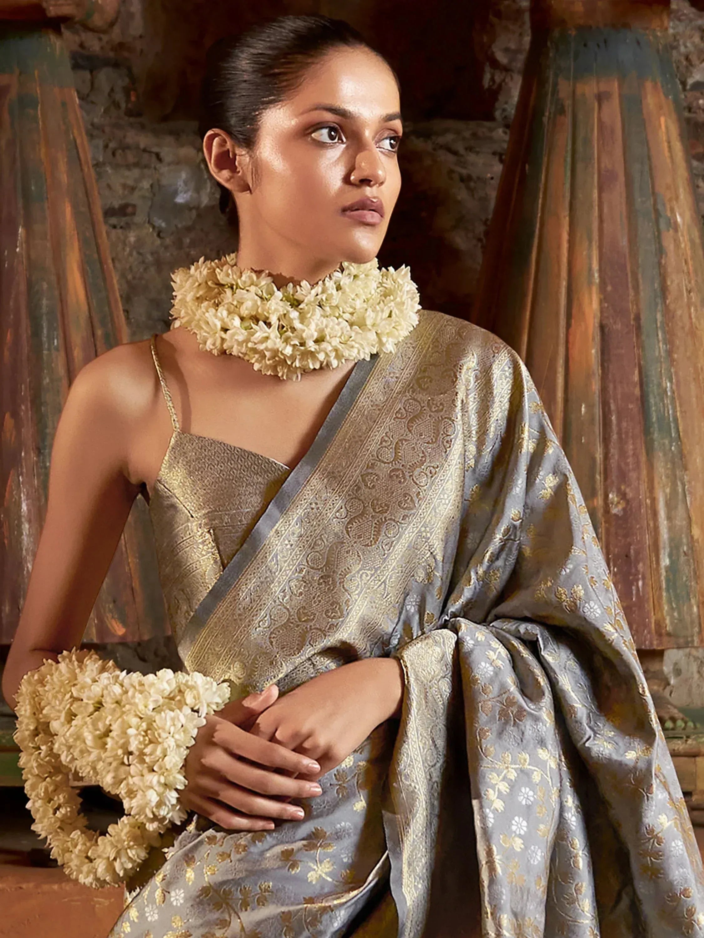Elegant woman in grey and gold embroidered saree with floral garlands, traditional Indian ethnic wear