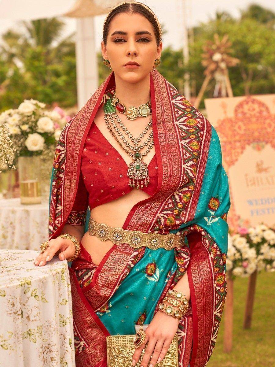 Red and teal designer lehenga choli with intricate embroidery, perfect for weddings and festive occasions.