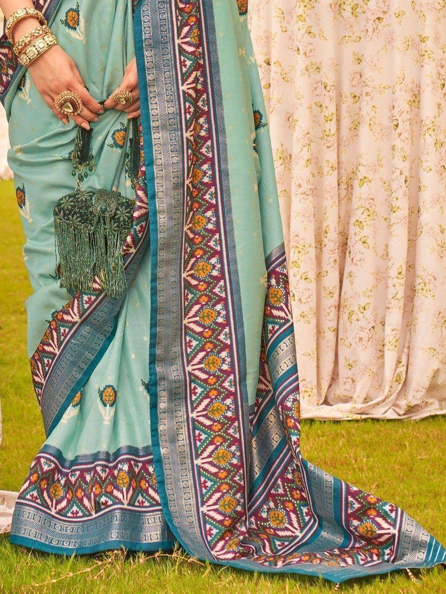 Turquoise ethnic saree with intricate border print, floral motifs, and tassel purse, styled for Indian occasions