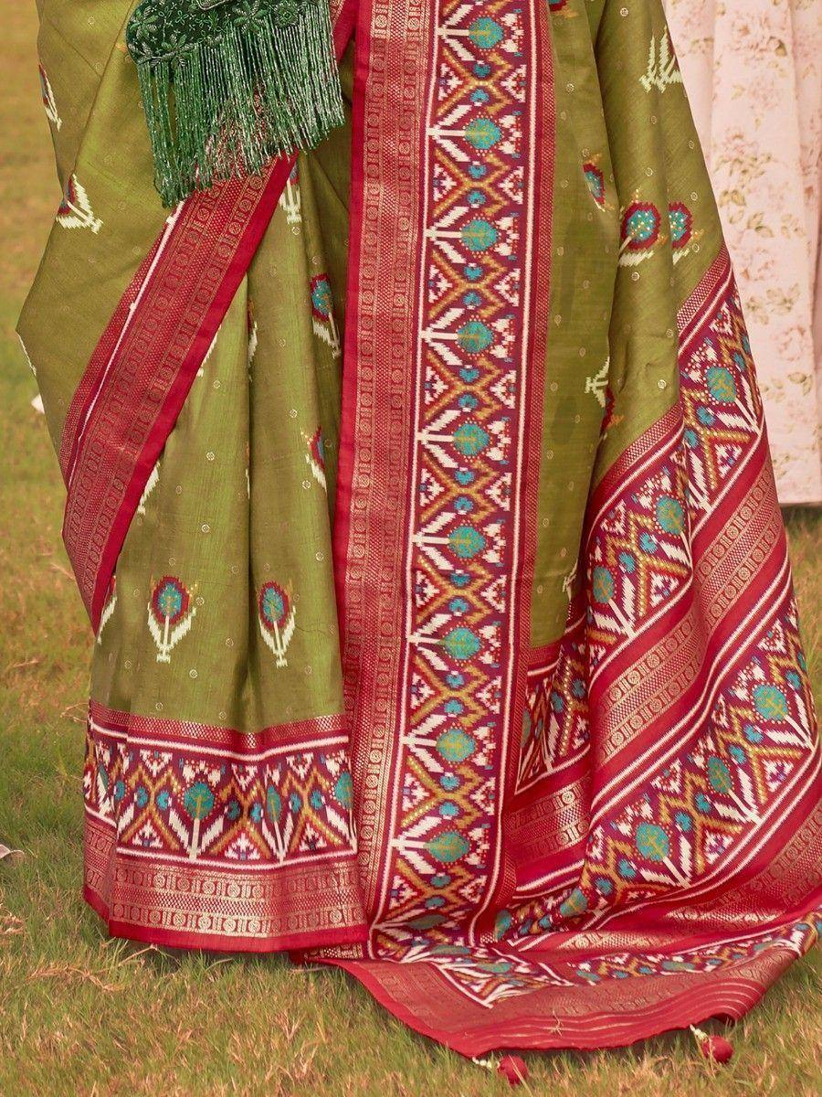 Olive green saree with red border, geometric ikat print, and tassel detail, perfect for ethnic occasions.