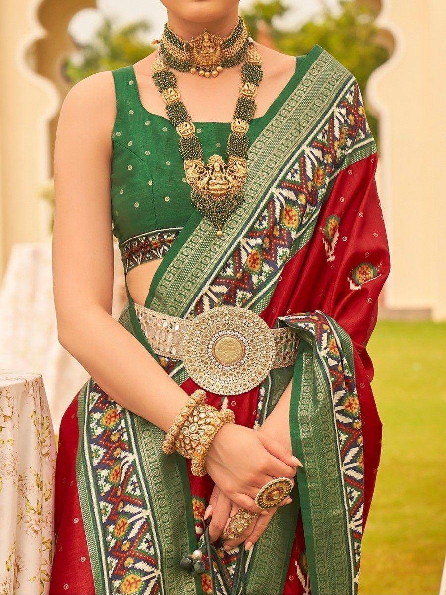 Green and red ethnic saree with intricate embroidery, gold jewelry, and designer belt for Indian weddings