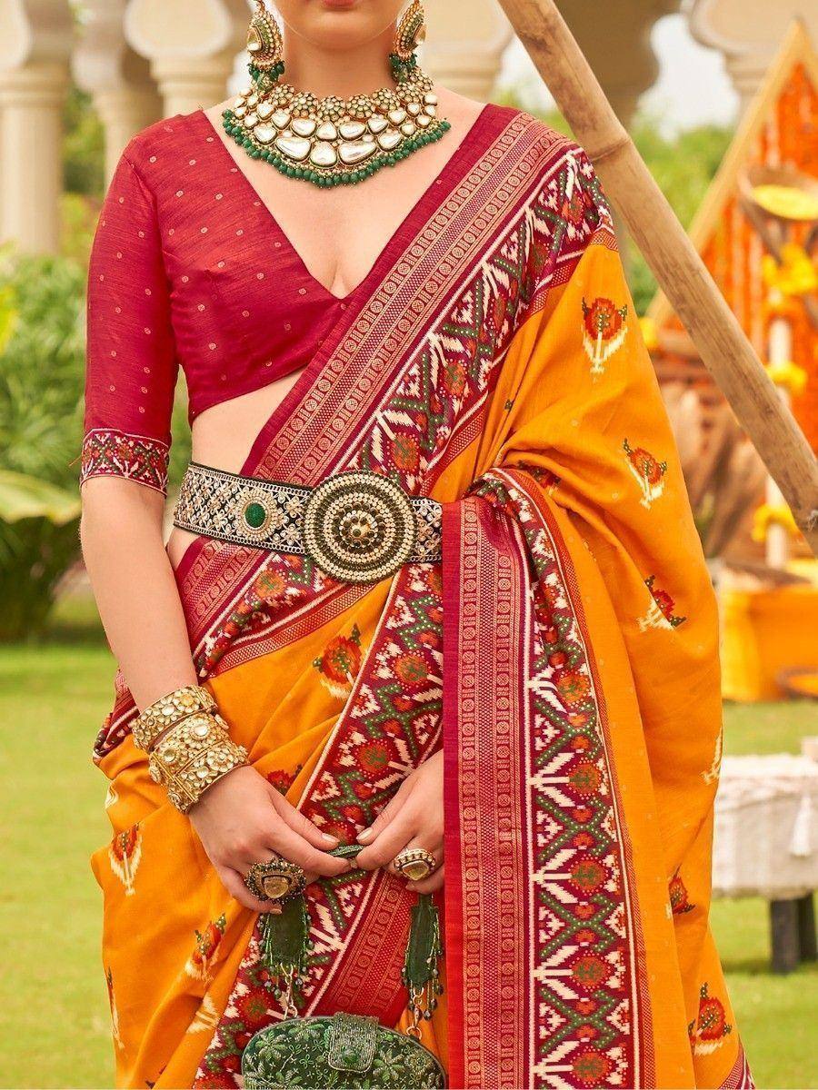 Vibrant orange and red ethnic saree with intricate embroidery, paired with designer jewelry for festive occasions