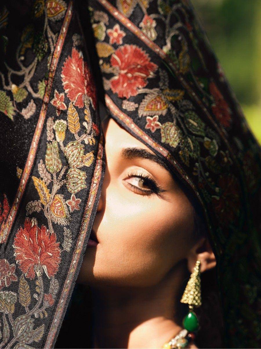 Elegant woman in floral embroidered ethnic dupatta with green gemstone earrings