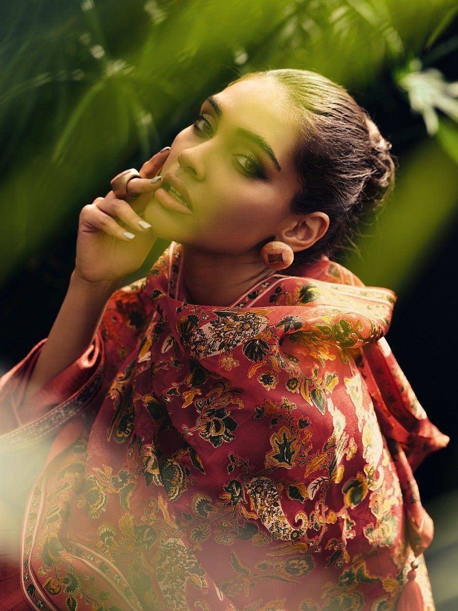 Woman in vibrant floral ethnic saree with green foliage backdrop