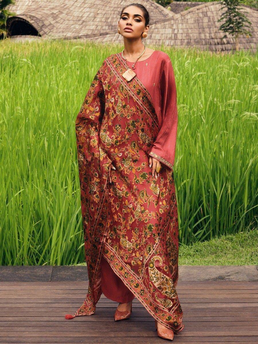 Woman in maroon floral printed ethnic kurta with palazzo pants, standing on wooden deck amidst green rice fields