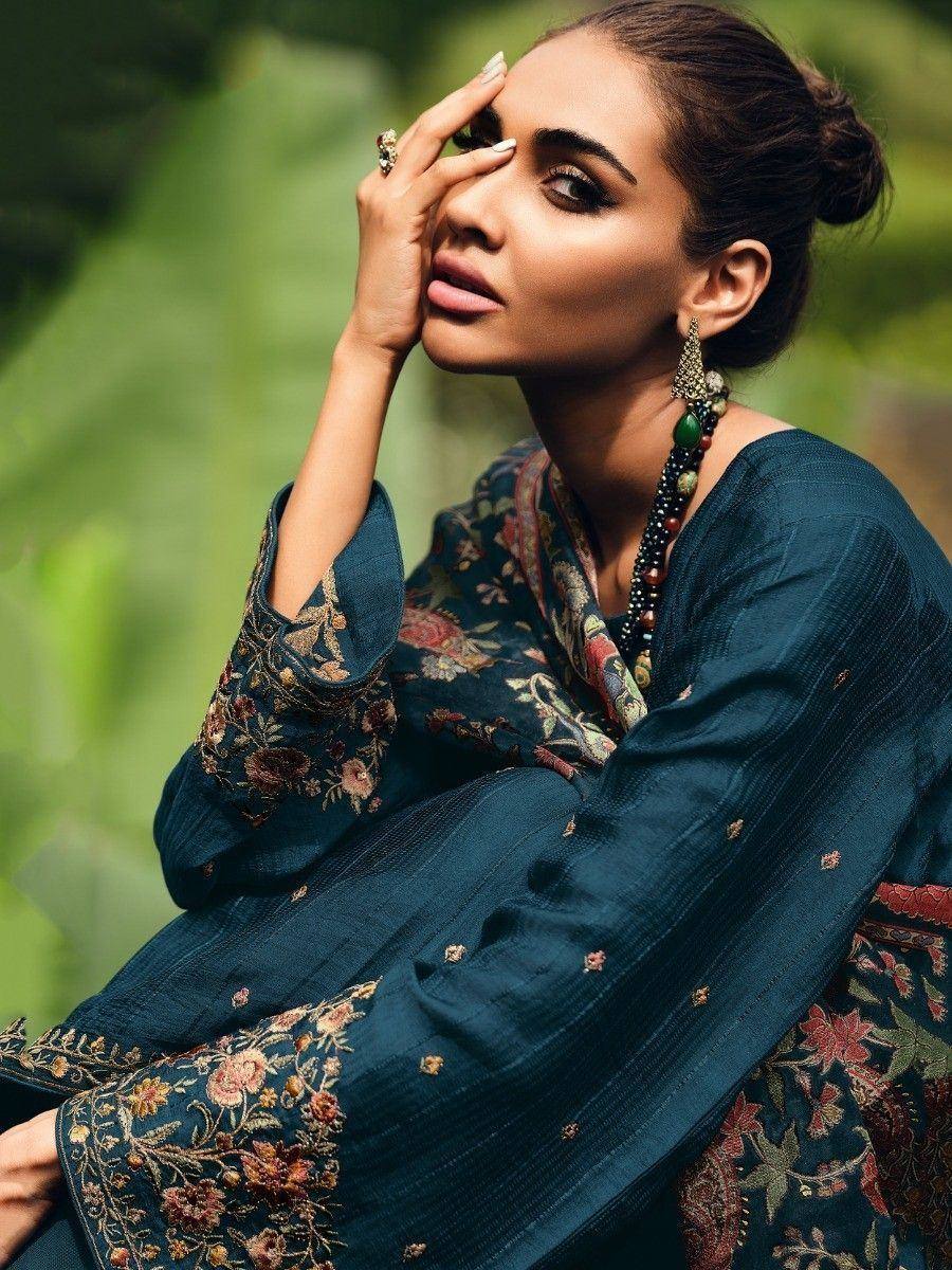 Woman in teal floral embroidered salwar kameez with matching dupatta and statement jewelry