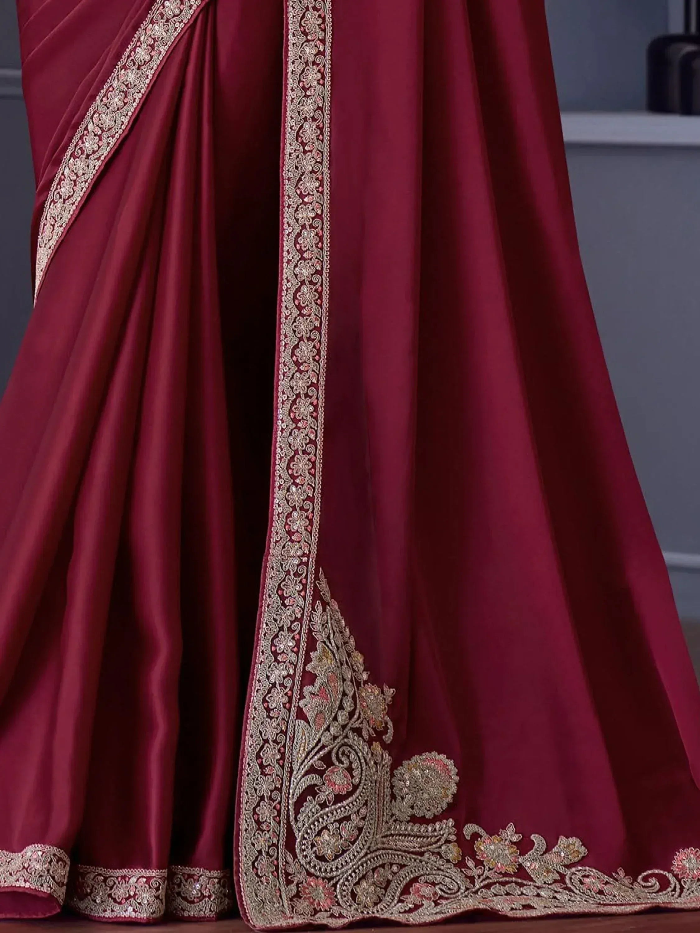 Rich maroon saree with intricate gold and pink floral embroidery, perfect for Indian ethnic occasions.
