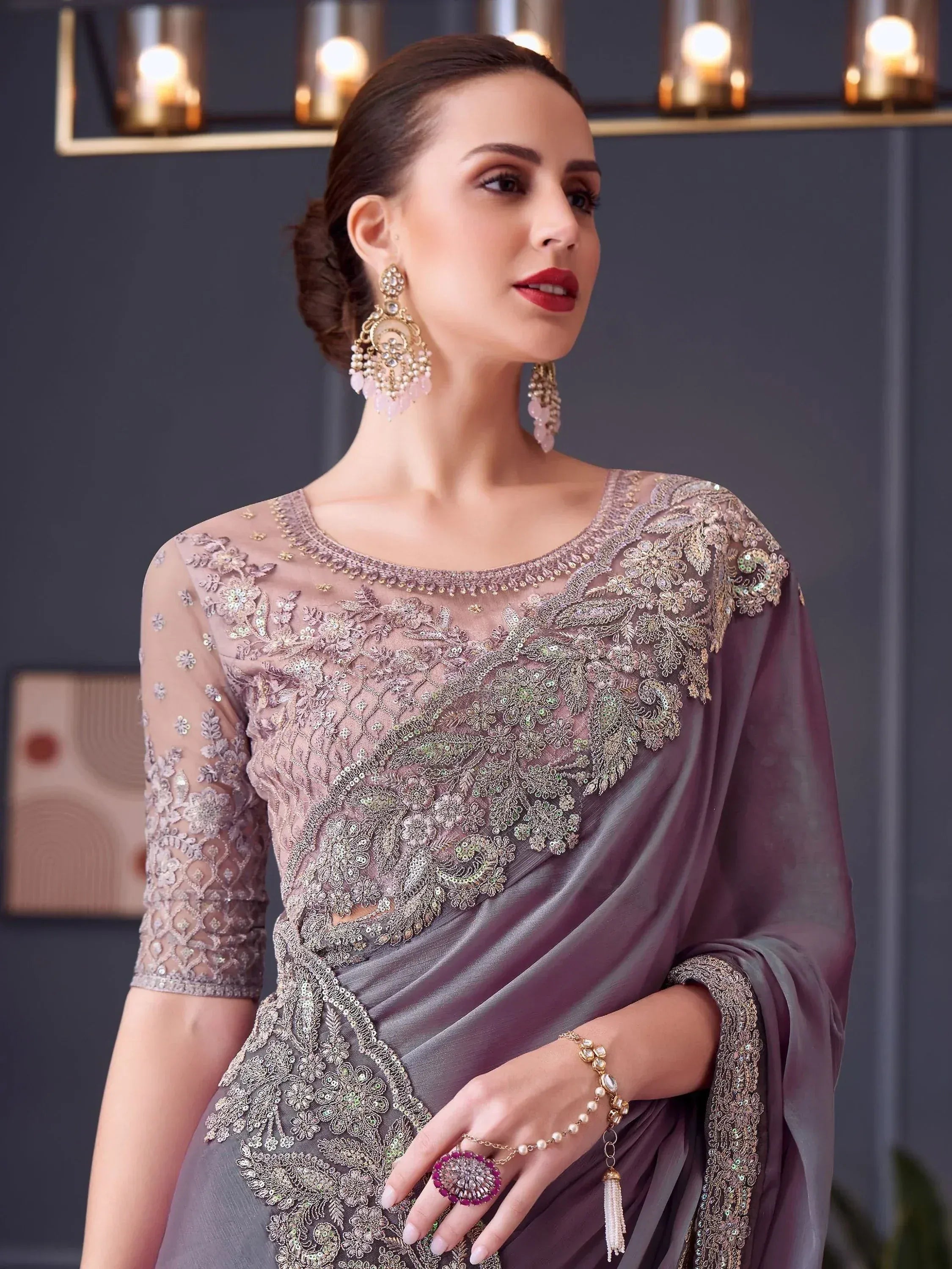 Elegant mauve saree with intricate gold embroidery and sheer sleeves, paired with statement jewelry for festive occasions.