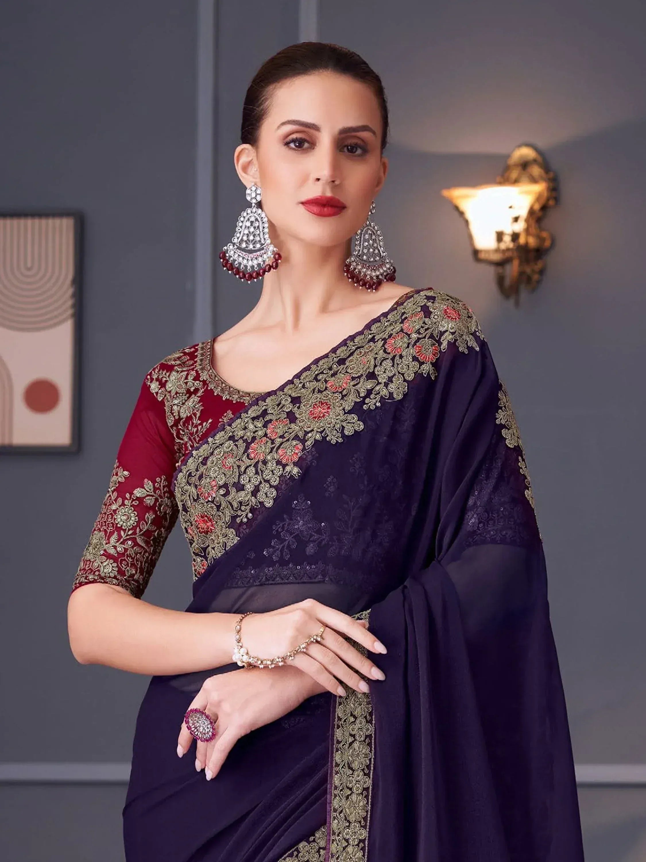 Elegant purple saree with gold floral embroidery and red blouse, paired with statement jewelry for Indian ethnic wear.