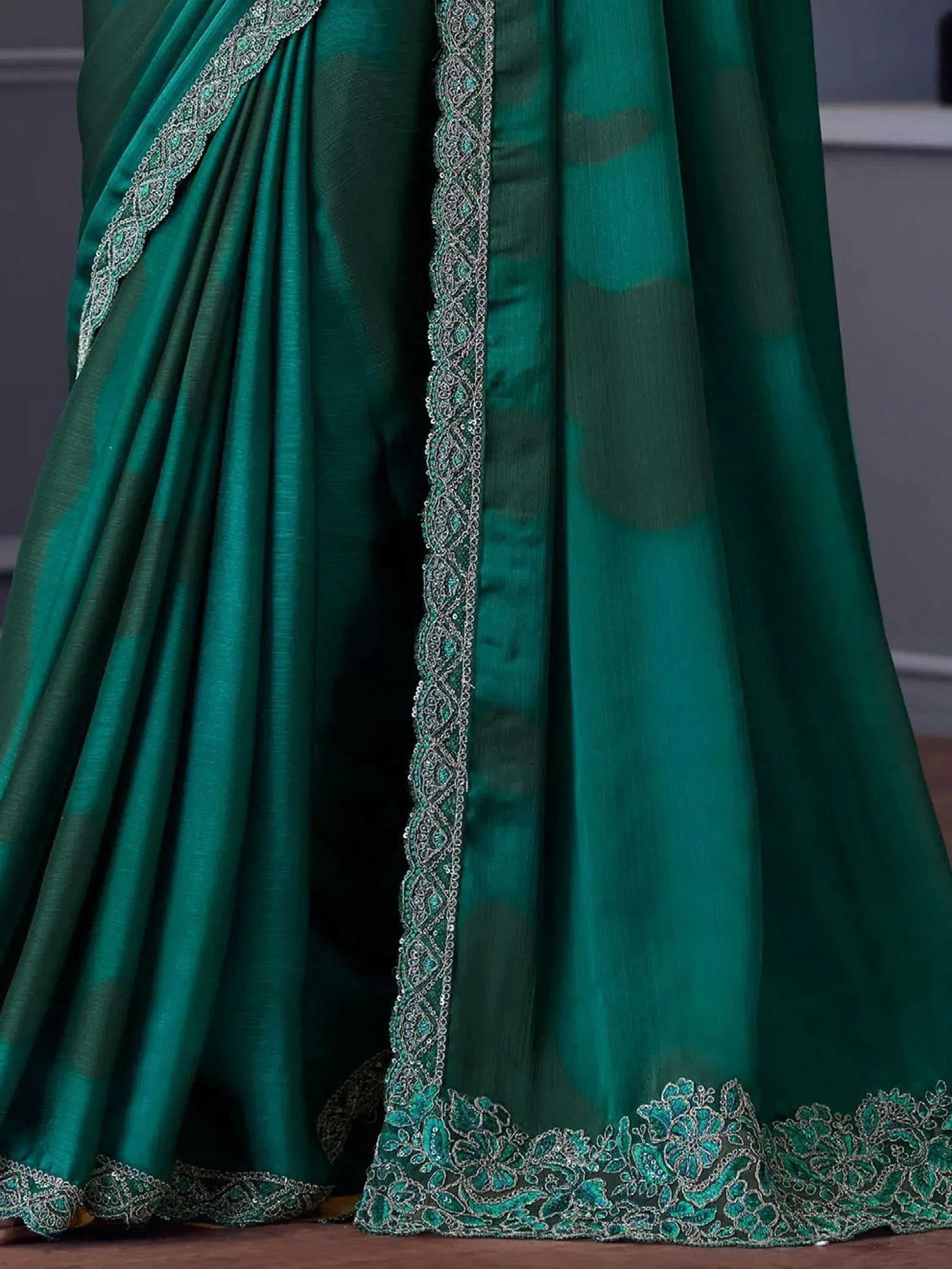 Emerald green saree with silver zari embroidery and floral border, ideal for Indian ethnic wear occasions.