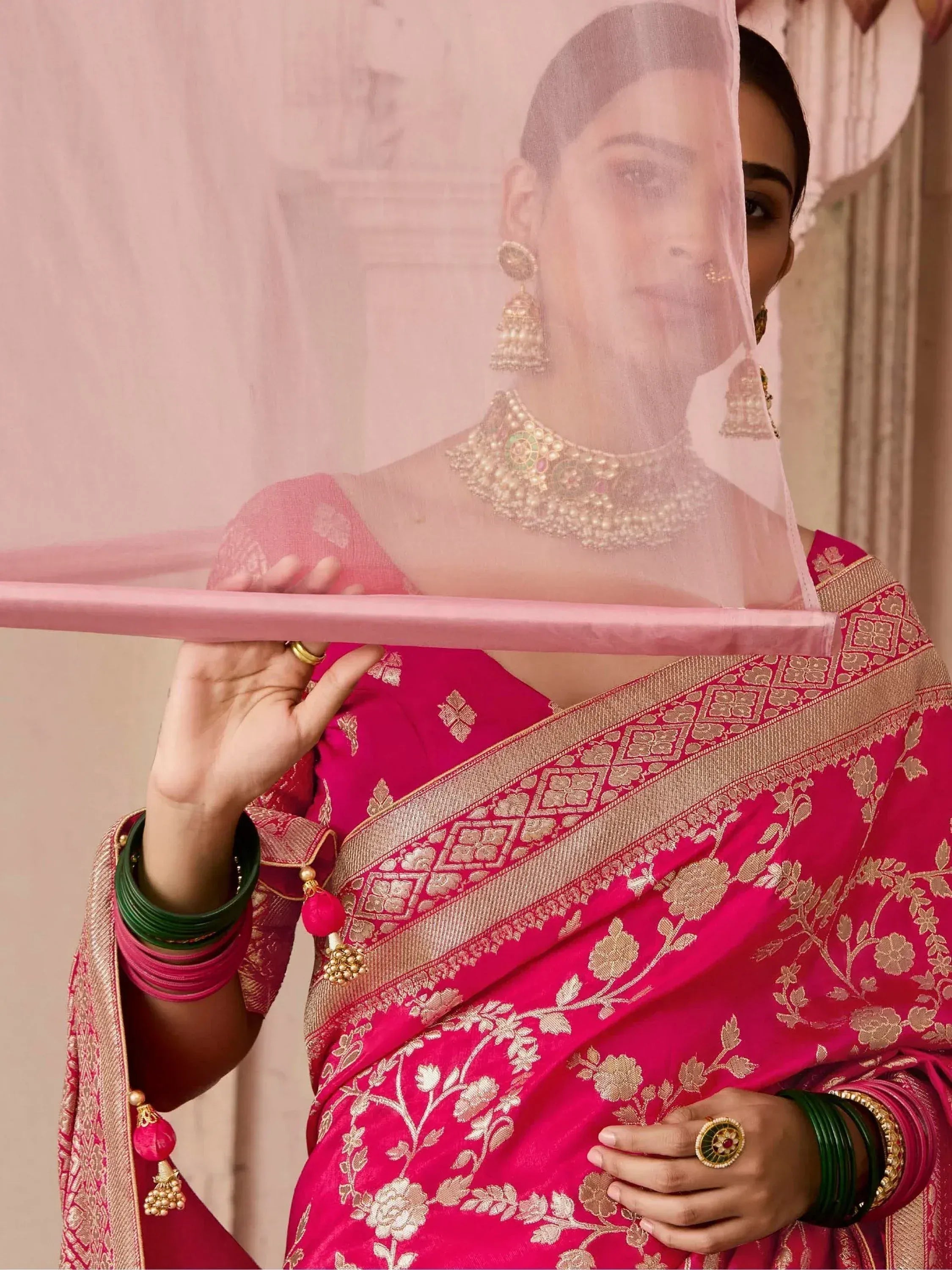 Woman in pink floral saree with gold embroidery, traditional Indian ethnic wear, green bangles, and temple jewelry