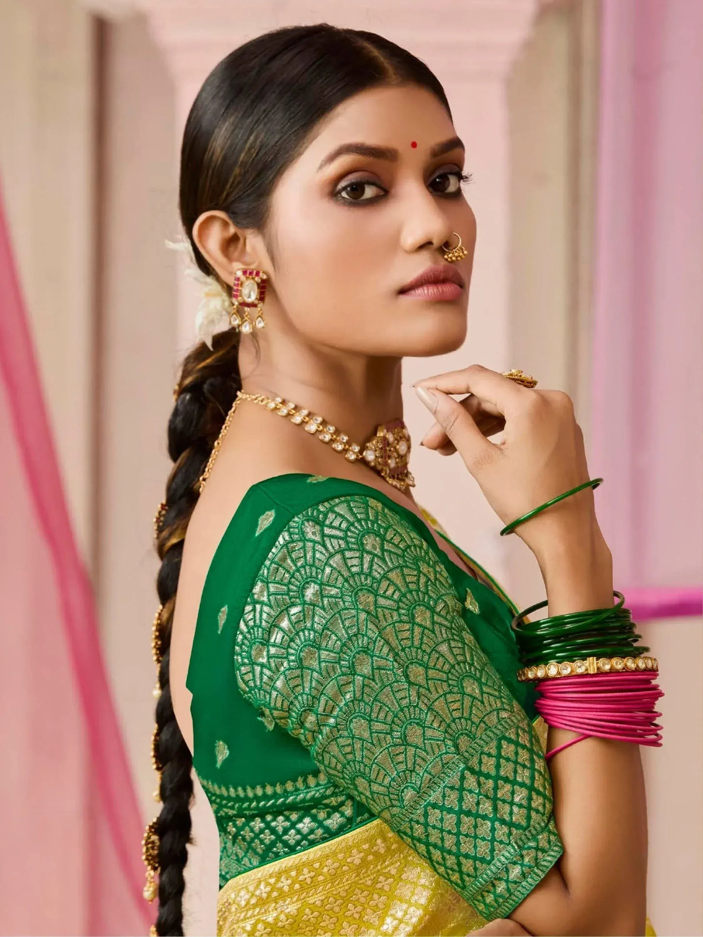 Woman in green and gold embroidered saree with traditional Indian jewelry and bangles