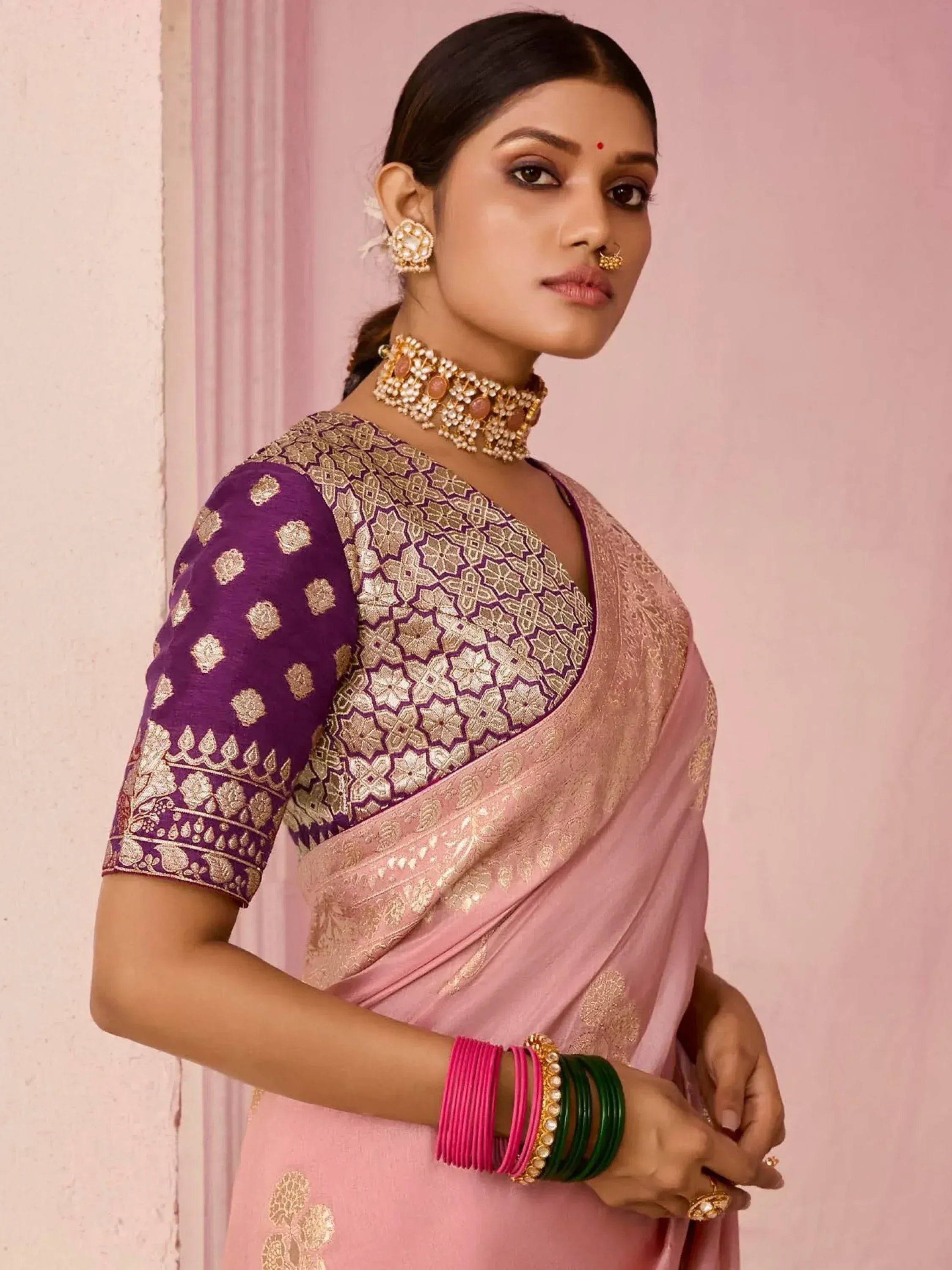 Elegant pink saree with gold embroidery and purple blouse, styled with traditional Indian jewelry for festive occasions