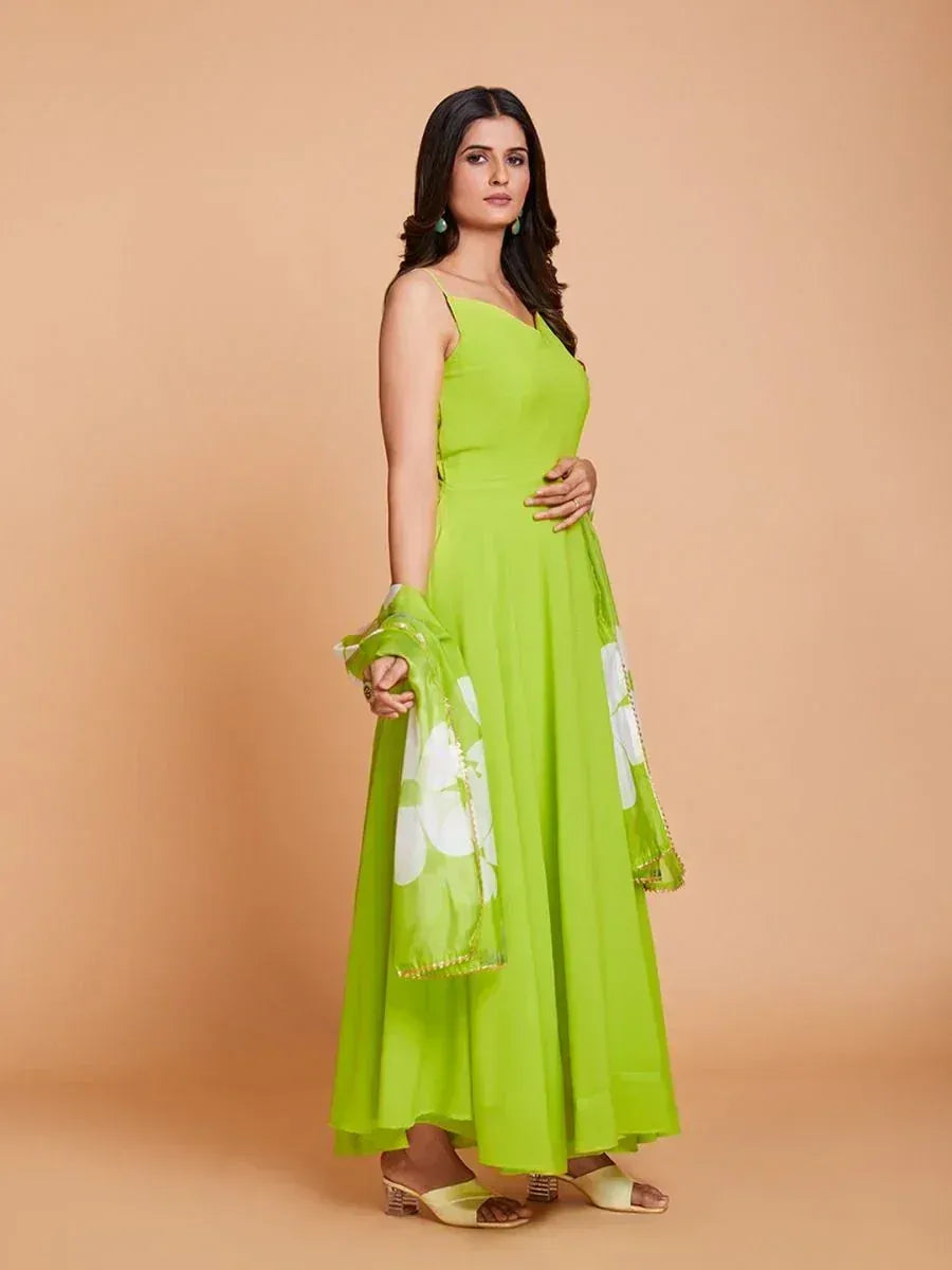 Woman in a lime green ethnic gown with matching dupatta and block heels, beige background
