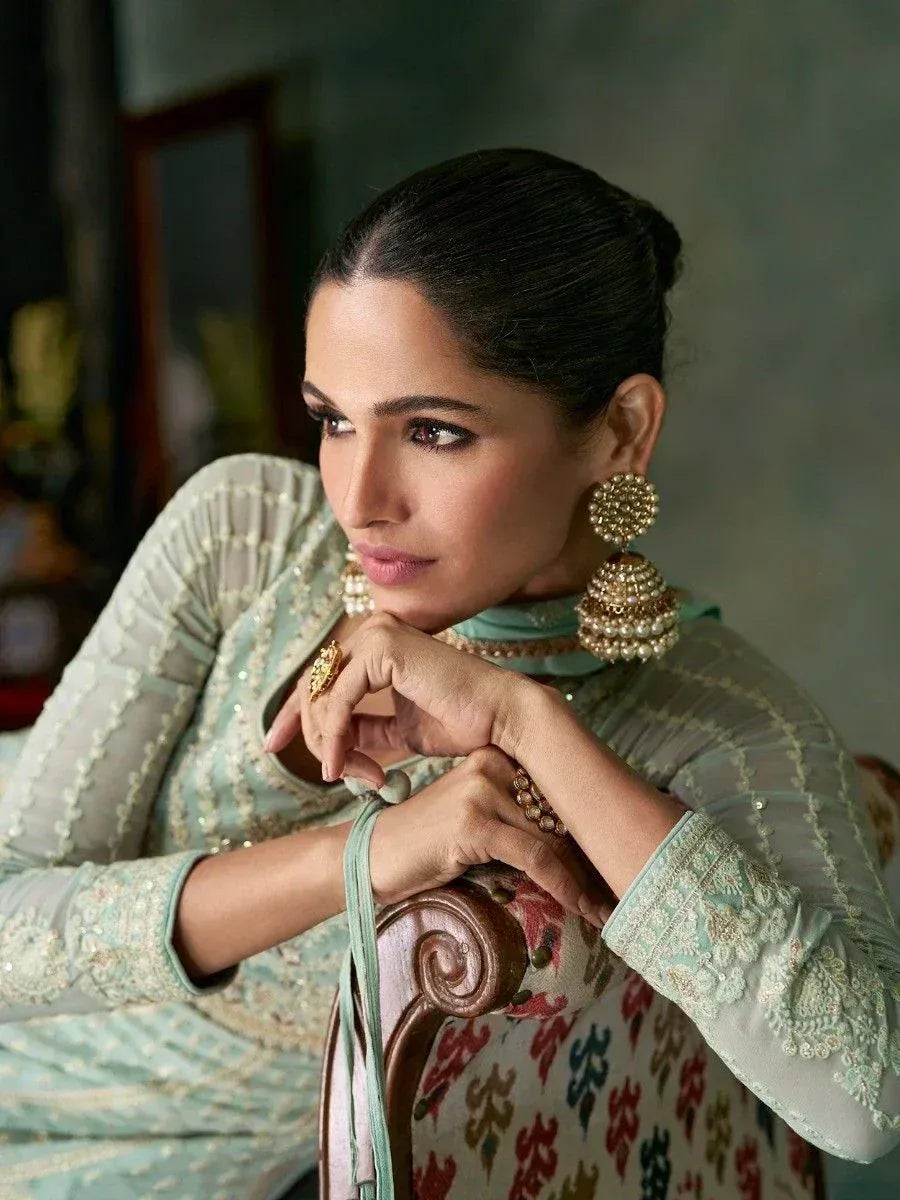 Elegant woman in mint green embroidered salwar kameez with pearl jhumka earrings, styled for festive occasions