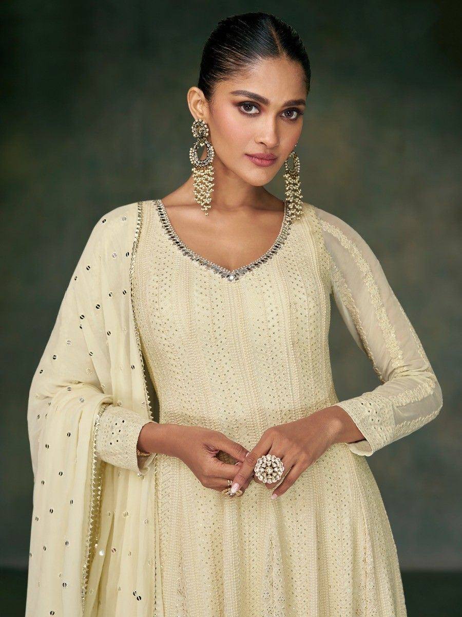 Elegant cream ethnic gown with mirror work and sheer sleeves, paired with statement jewelry