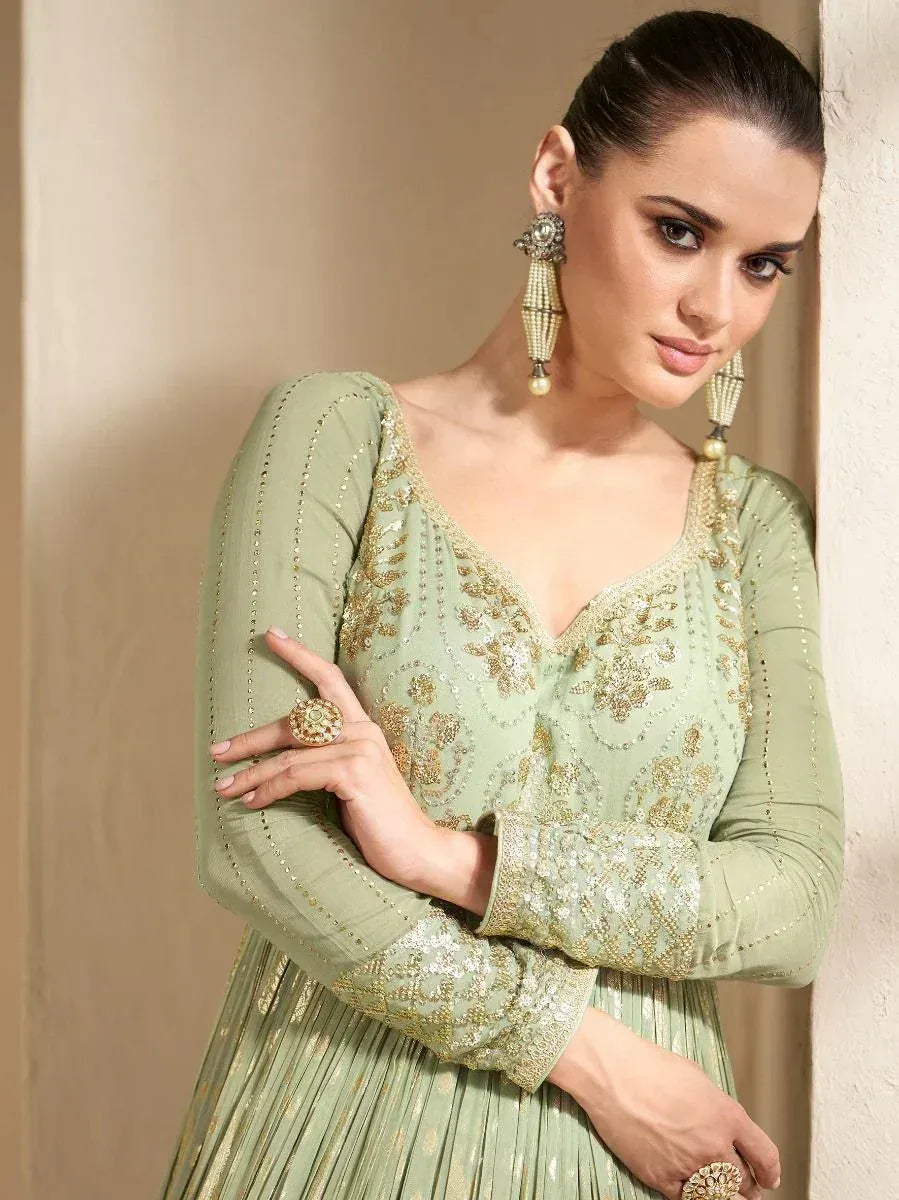 Mint green embroidered ethnic gown with gold detailing, perfect for Indian weddings and festive occasions.