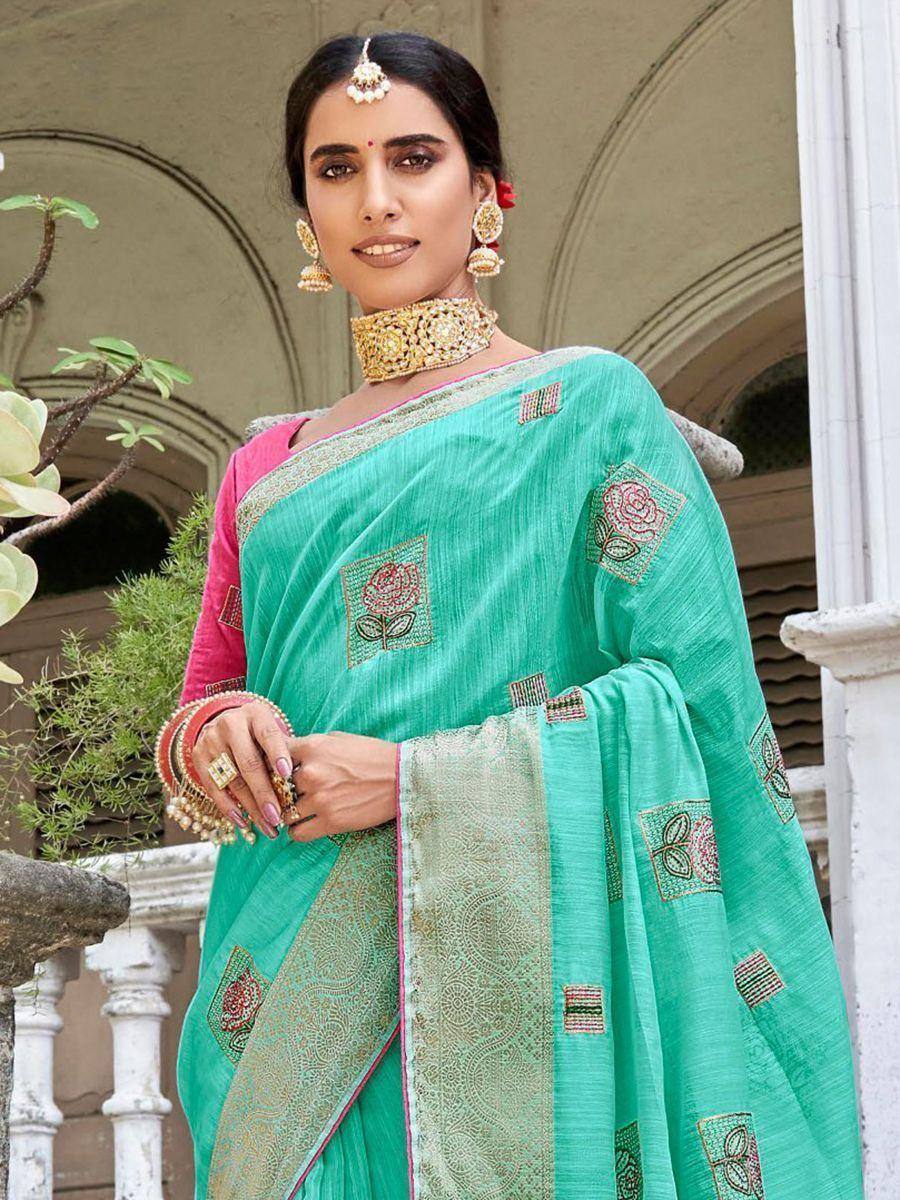 Turquoise saree with floral embroidery and gold border, paired with pink blouse and traditional jewelry