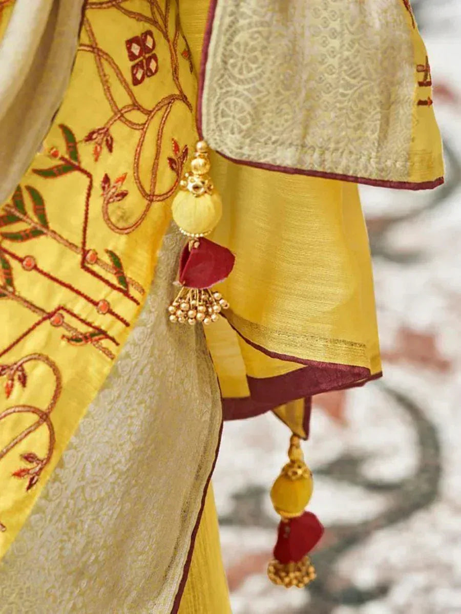 Yellow ethnic saree with floral embroidery and gold tassels
