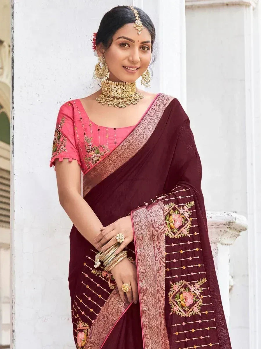 Maroon embroidered saree with pink blouse, floral motifs, and gold jewelry for Indian ethnic wear