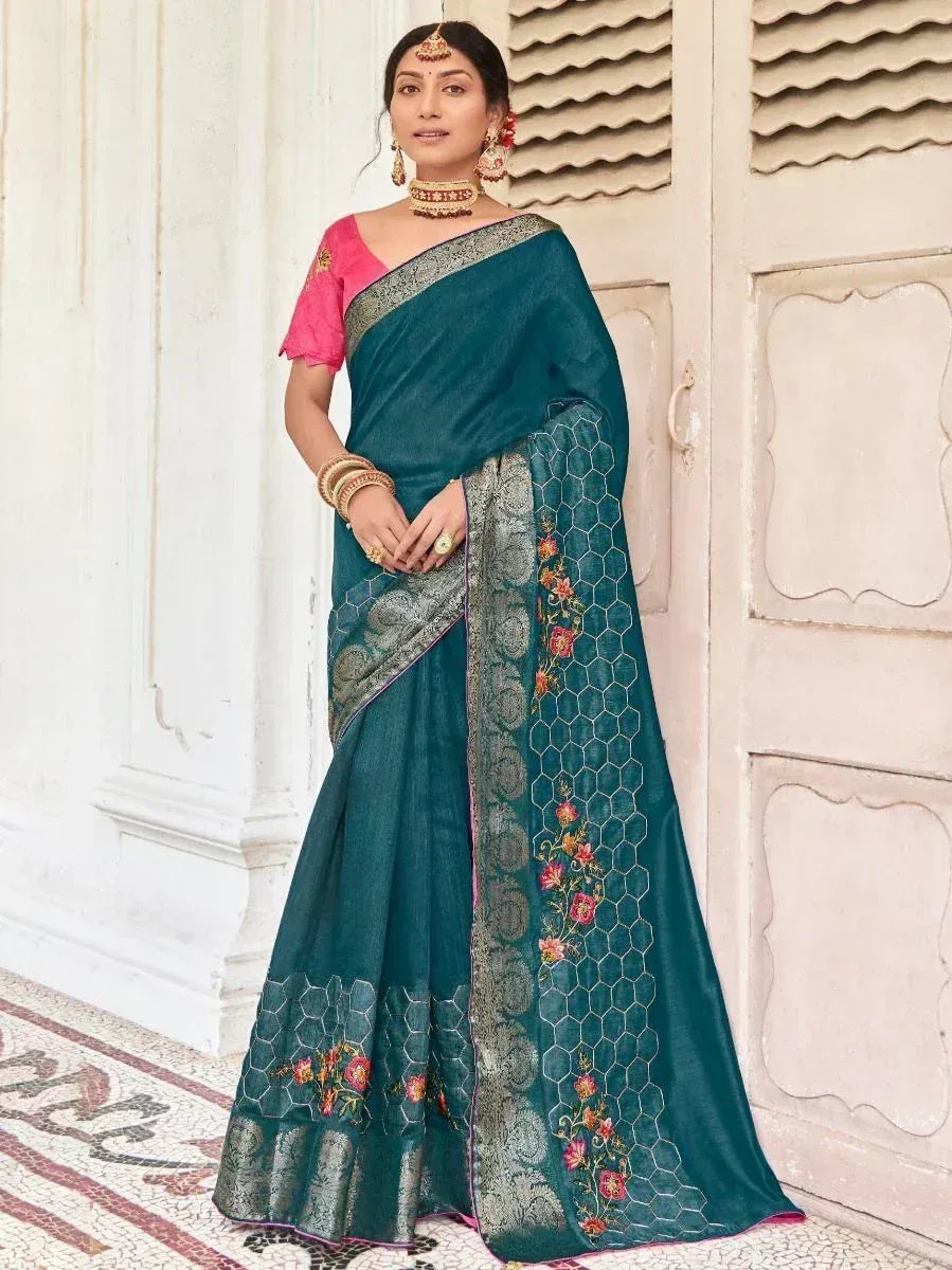 Teal designer saree with floral embroidery and pink blouse, styled with traditional jewelry for ethnic wear.