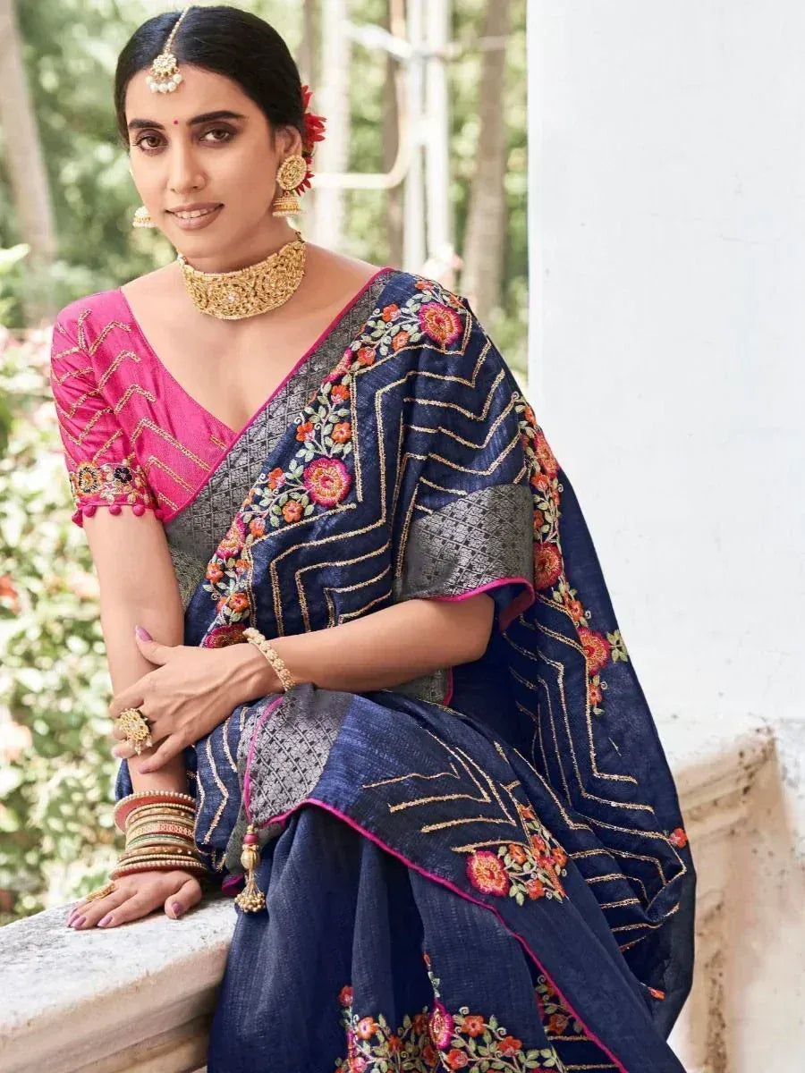Woman in navy blue embroidered saree with pink blouse, floral motifs, and gold jewelry, styled for ethnic occasions