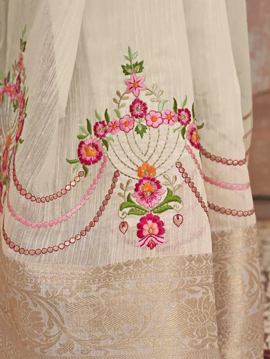 Cream ethnic gown with pink floral embroidery and gold border, perfect for Indian occasions