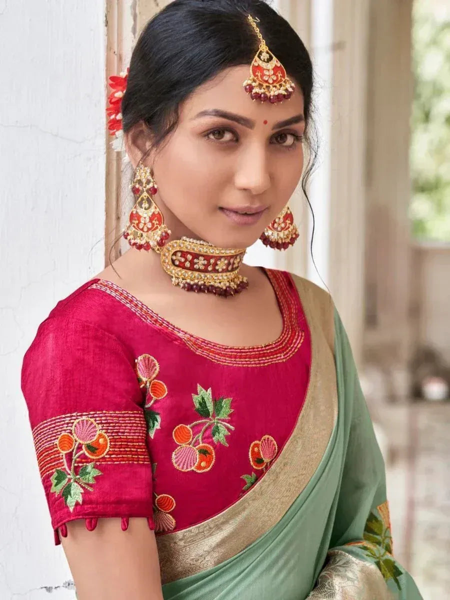 Woman in red embroidered blouse with green saree, traditional Indian ethnic wear, floral motifs, gold jewelry