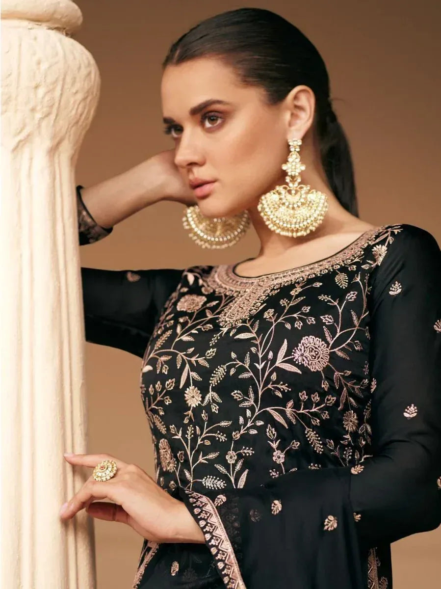 Black embroidered ethnic gown with gold floral detailing, paired with statement jhumka earrings for festive occasions