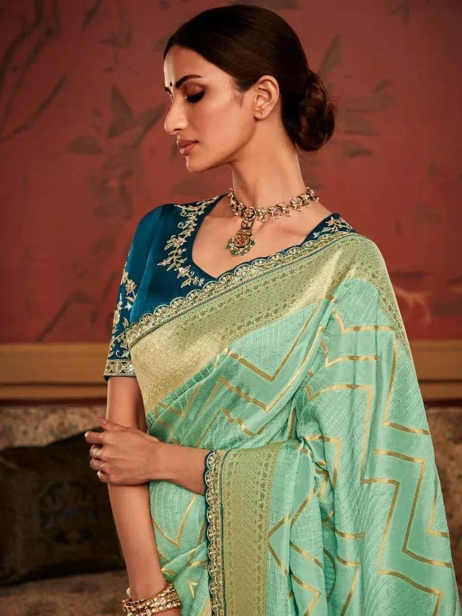 Mint green saree with gold geometric print and blue embroidered blouse, styled with traditional jewelry