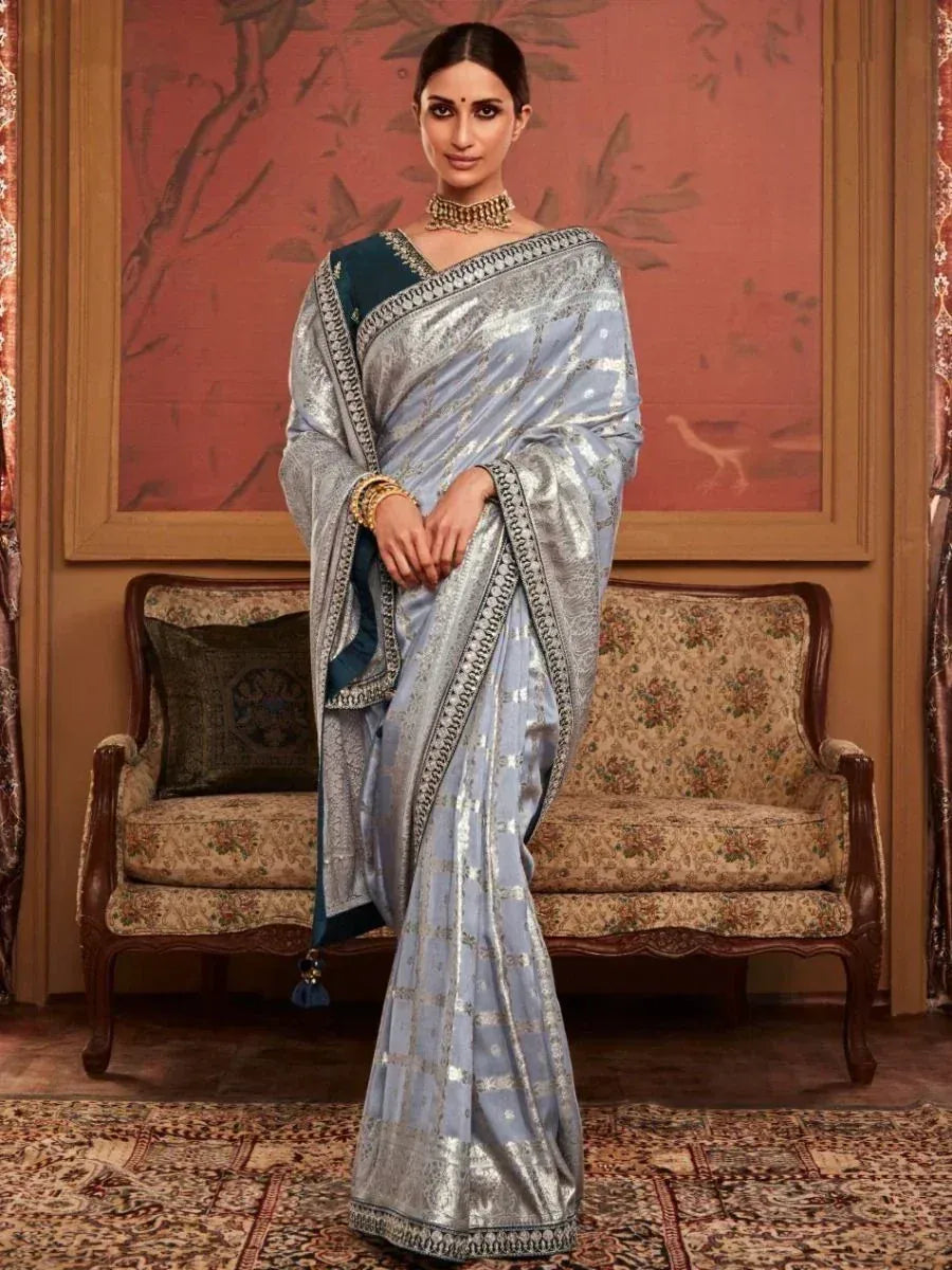 Elegant light blue saree with silver zari border, paired with dark blue blouse, perfect for Indian ethnic occasions.